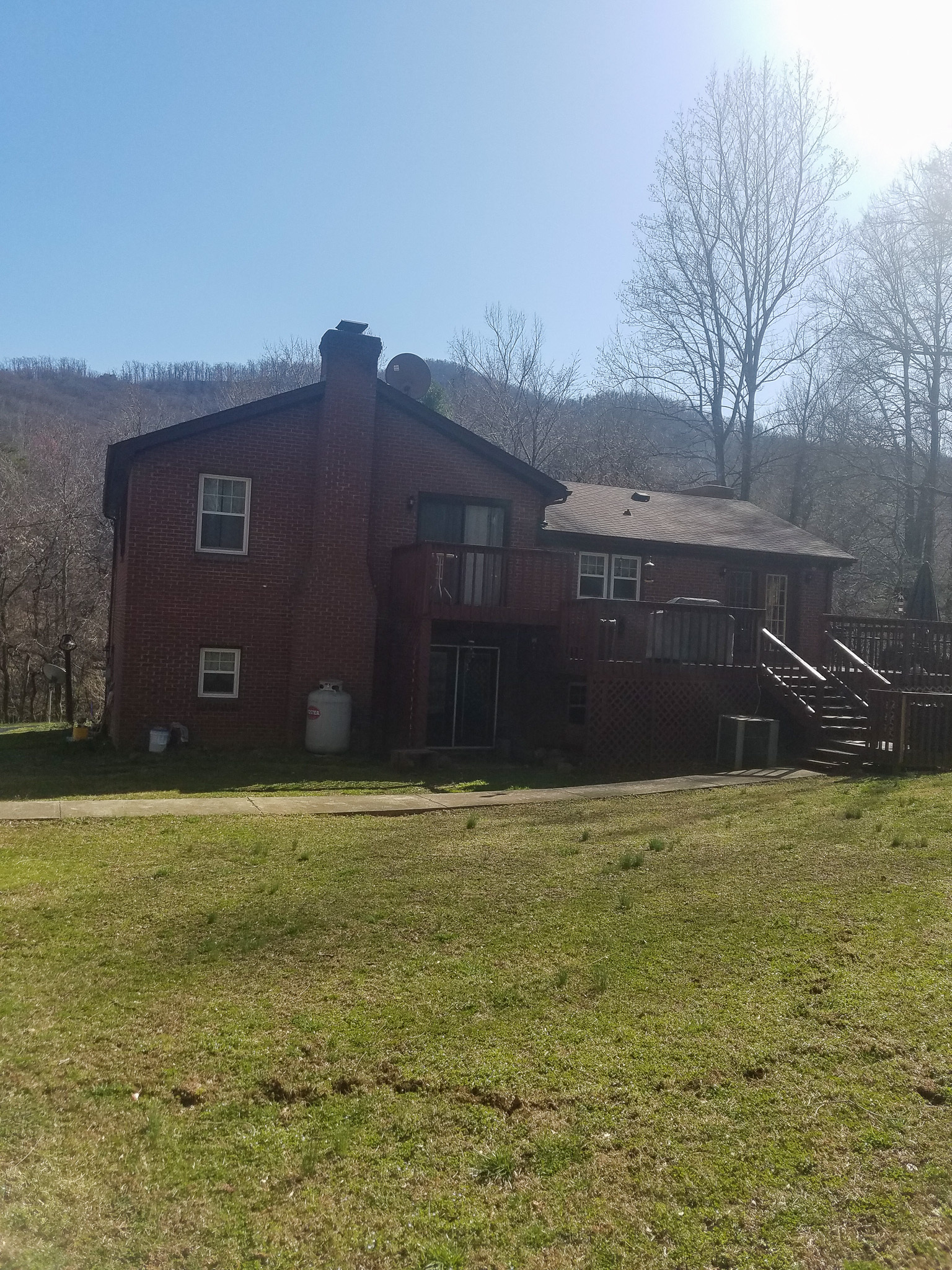Two‑story brick house with a raised wooden deck, bare trees, and a large grassy yard belonging to Sponsored Residential Provider Sharon Litchford in Monroe, Virginia