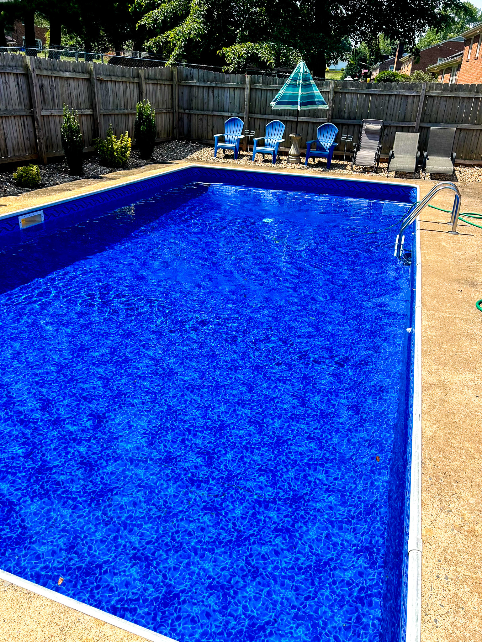 Bright blue in‑ground pool with clear water, surrounded by concrete decking, lounge chairs, and a fenced backyard at the home of Sponsored Residential Providers Takeyshia Gibson and Antonio Carter in Forest, Virginia.