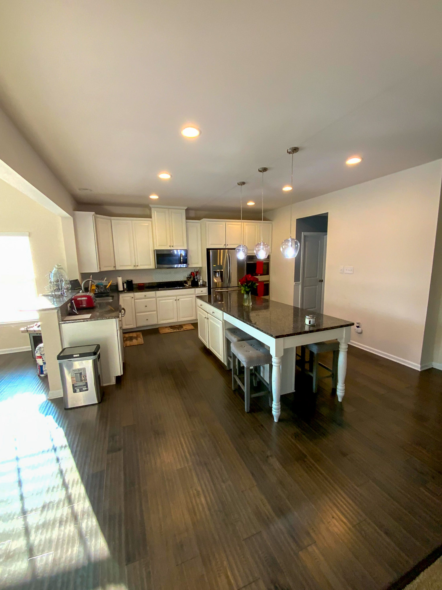 A bright kitchen features white cabinetry, a large center island, and stainless steel appliances arranged along the walls inside the home of Sponsored Residential Provider Derrick Moseley in Richmond, Virginia.