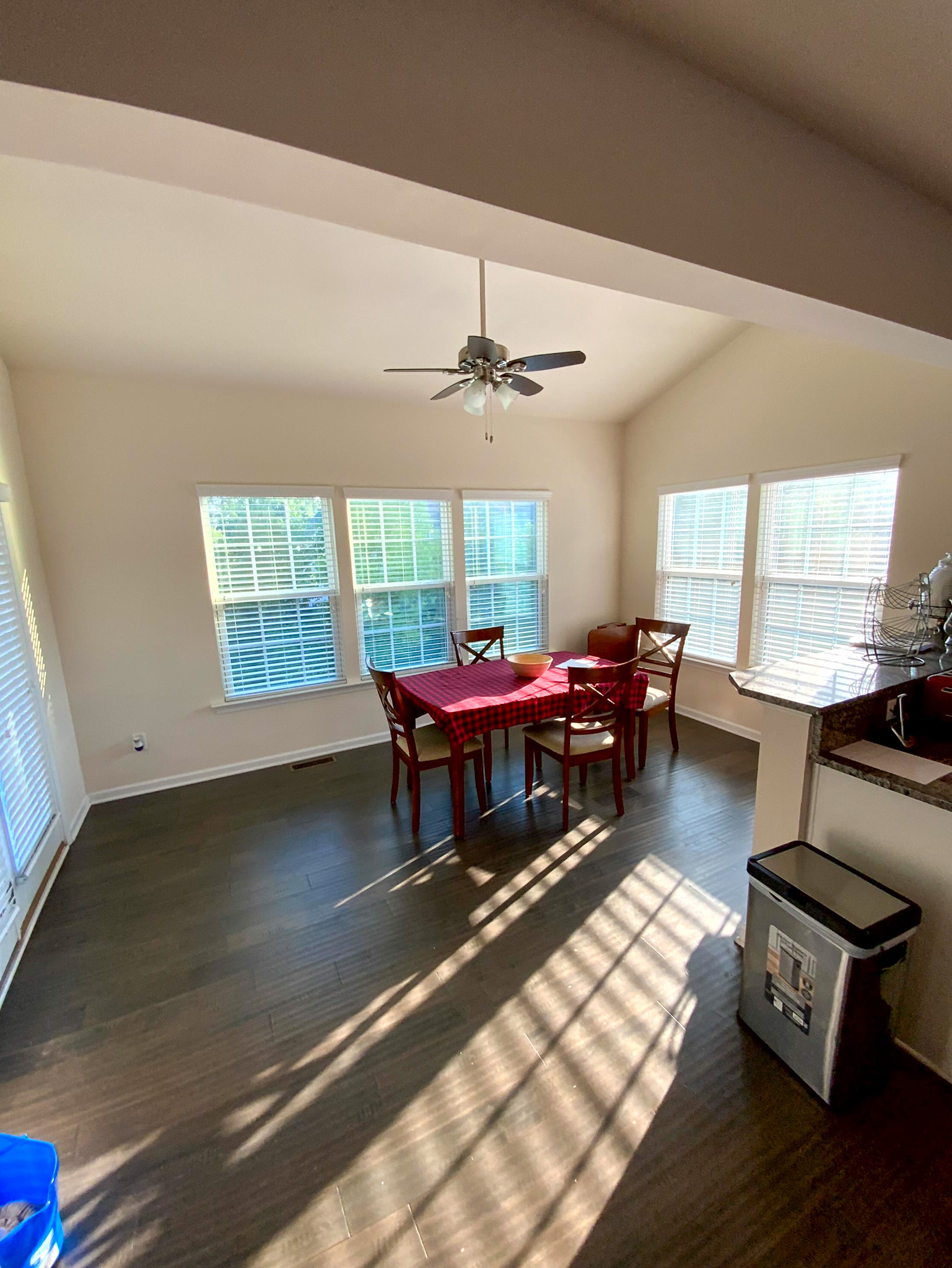 A bright breakfast area features a small dining table with four chairs, surrounded by large windows that fill the space with light inside the home of Sponsored Residential Provider Derrick Moseley in Richmond, Virginia.