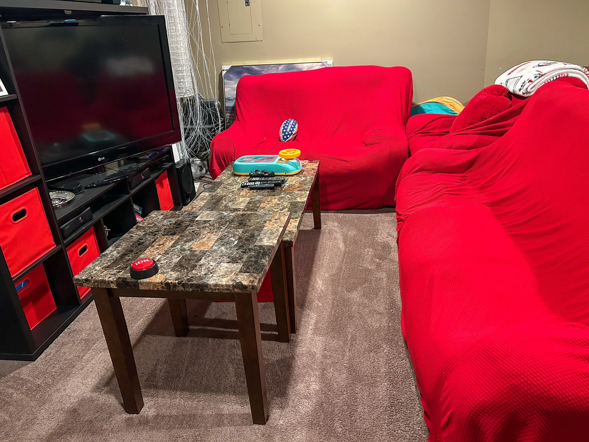 Basement seating area with red-covered sofas, coffee table, and television unit inside the home of Sponsored Residential Provider Aidah Brassier in Spotsylvania, VA.