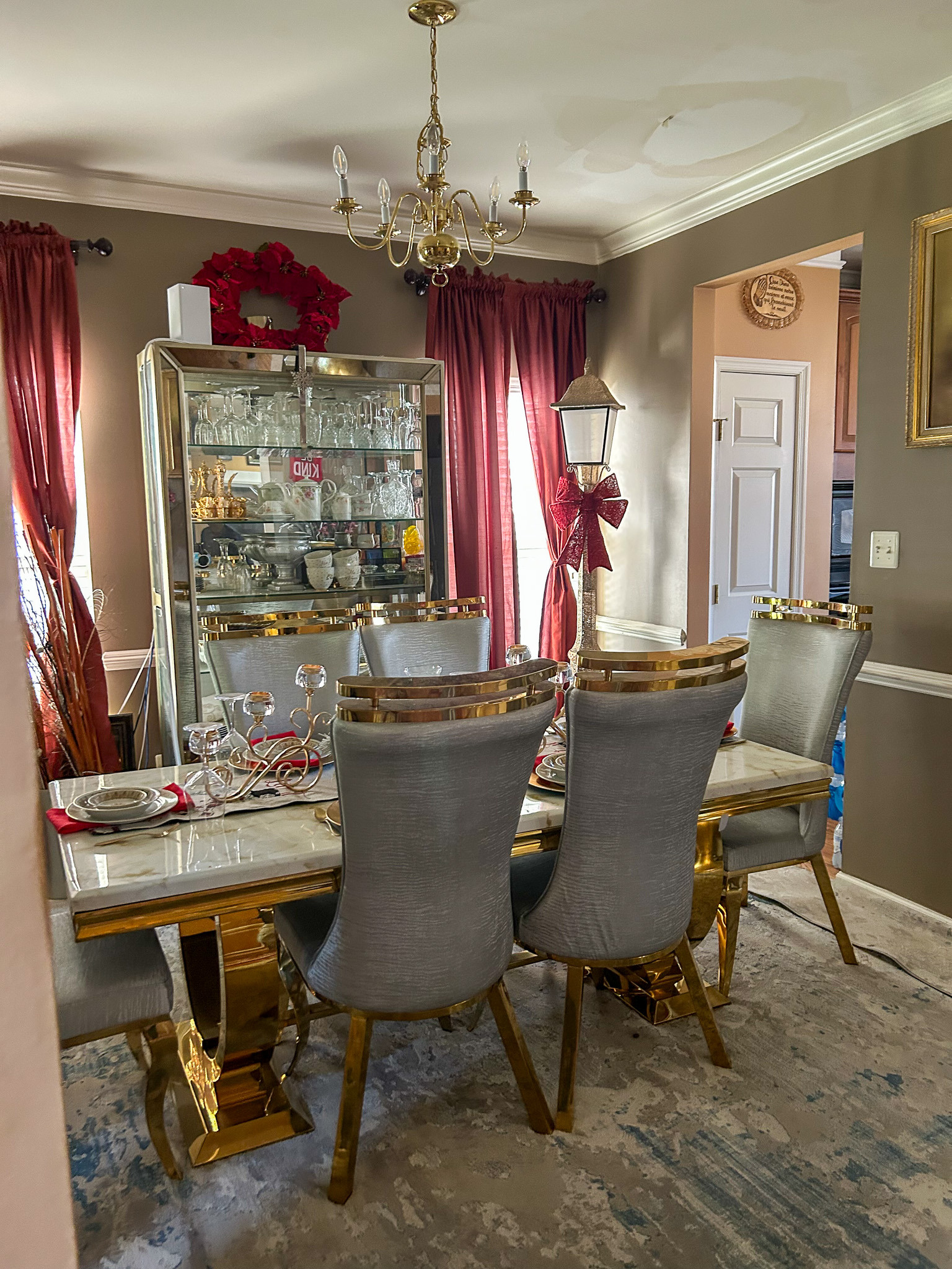 Formal dining room with marble-top table, upholstered chairs, china cabinet, and chandelier inside the home of Sponsored Residential Provider Aidah Brassier in Spotsylvania, VA.