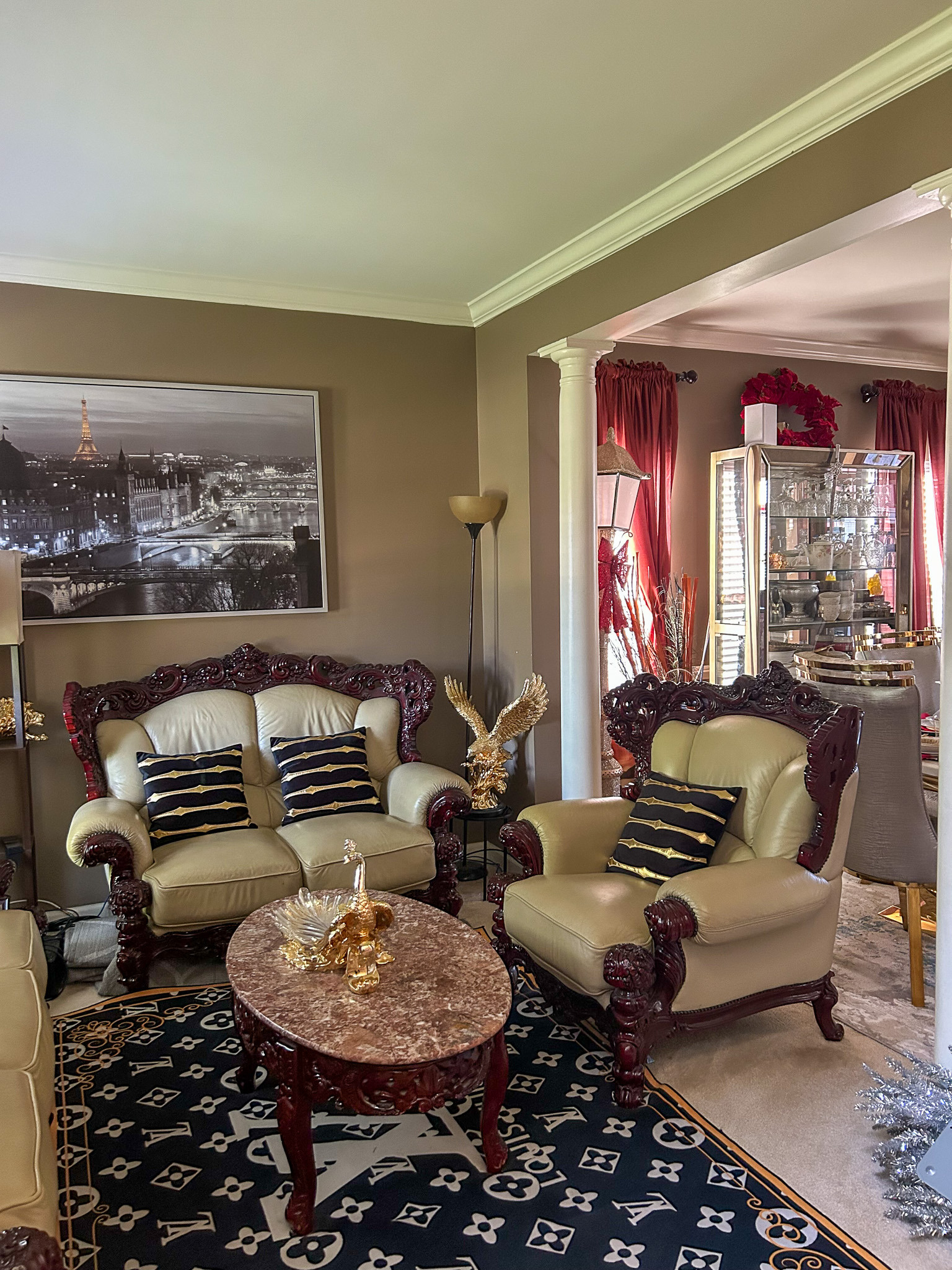 Living room with ornate armchairs, loveseat, round coffee table, and framed wall art inside the home of Sponsored Residential Provider Aidah Brassier in Spotsylvania, VA.