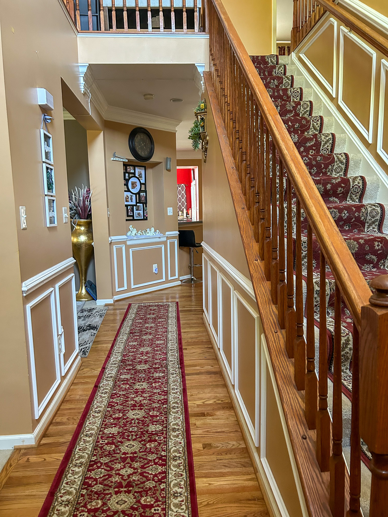 Front hallway with hardwood floors, runner rug, staircase, and decorative wall molding inside the home of Sponsored Residential Provider Aidah Brassier in Spotsylvania, VA.