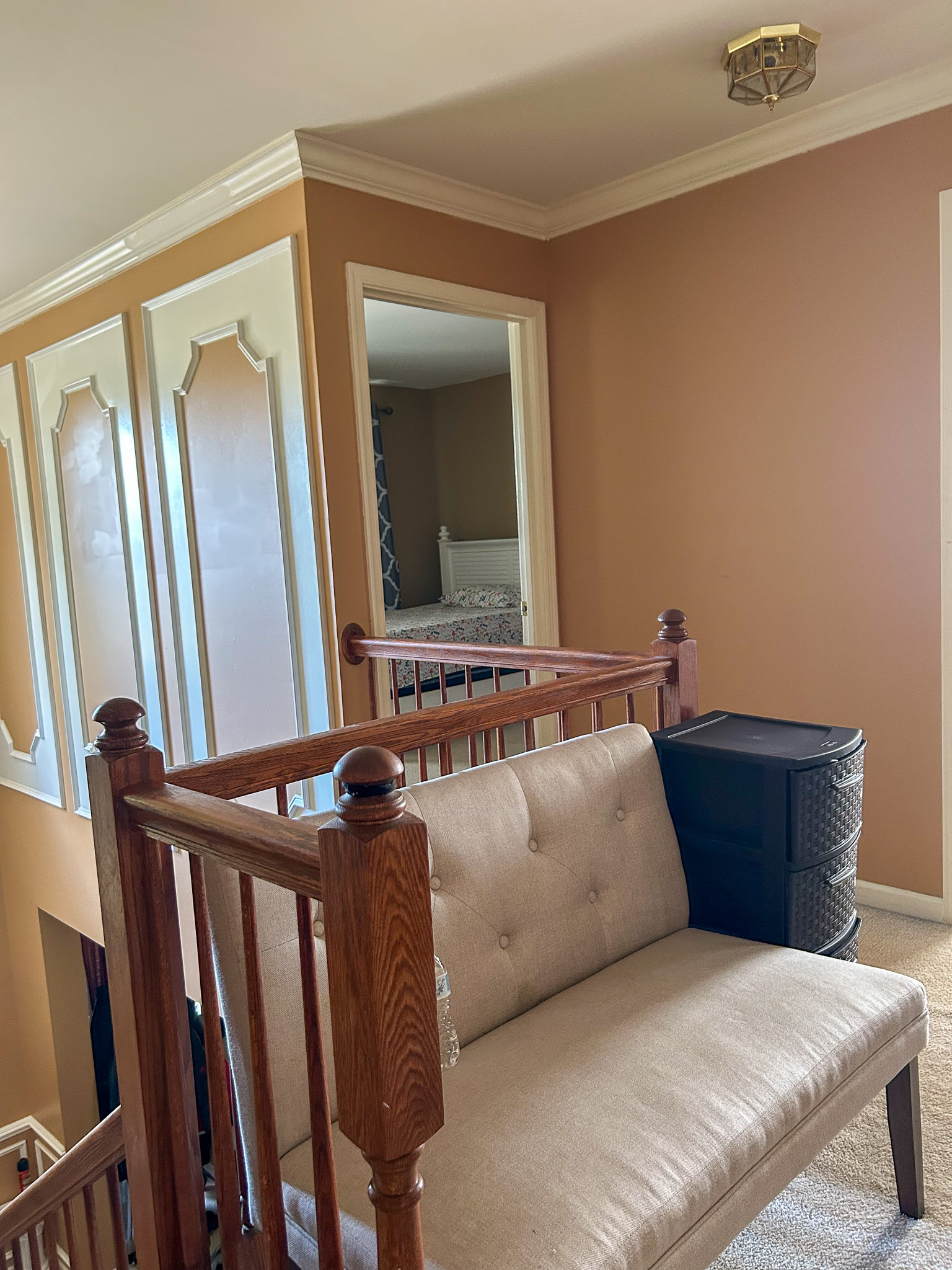 Upstairs landing with bench seating, stair railing, and view into a bedroom doorway inside the home of Sponsored Residential Provider Aidah Brassier in Spotsylvania, VA.