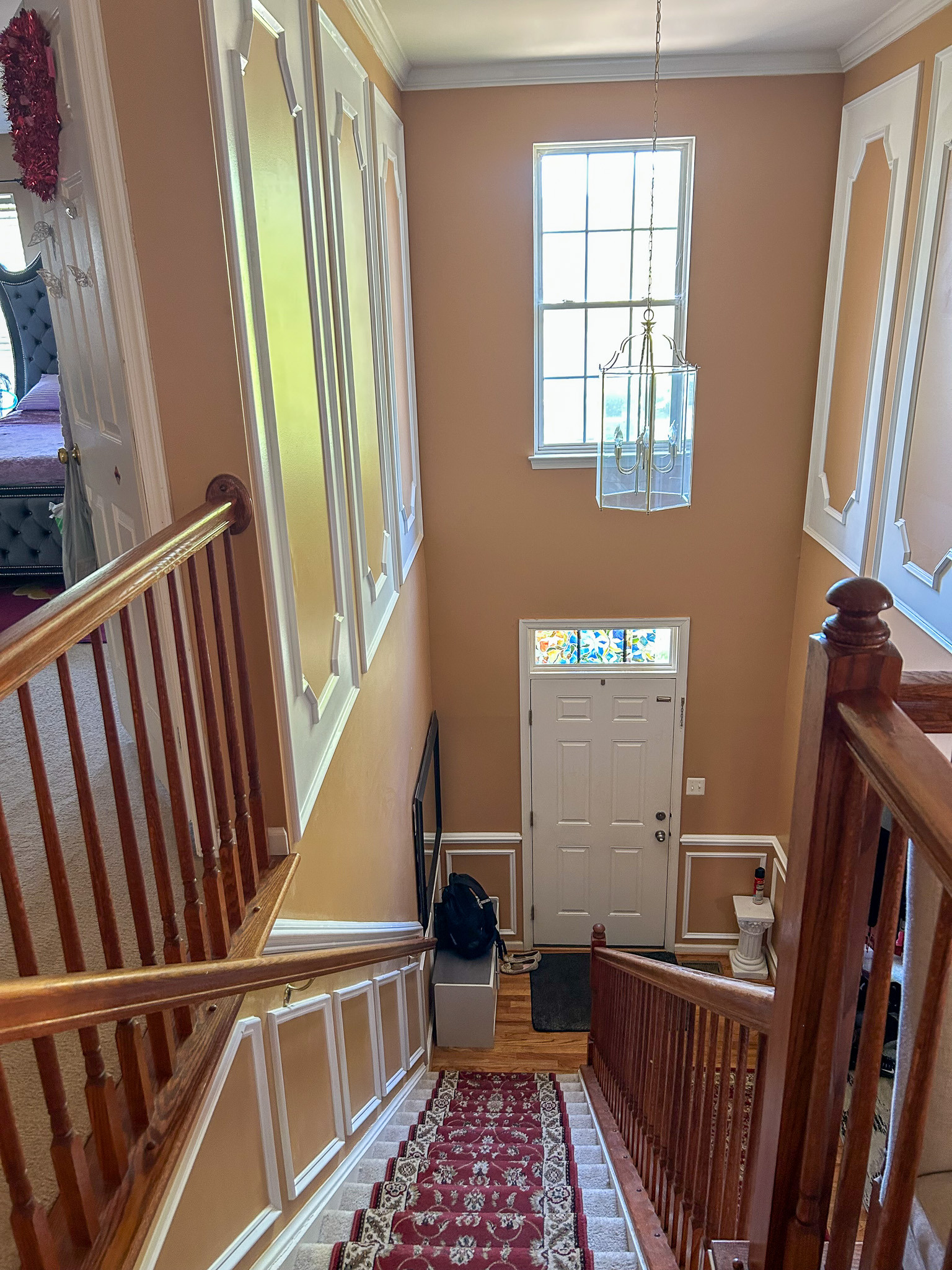 Staircase view looking down to the front entry with runner carpet and hanging light fixture inside the home of Sponsored Residential Provider Aidah Brassier in Spotsylvania, VA.