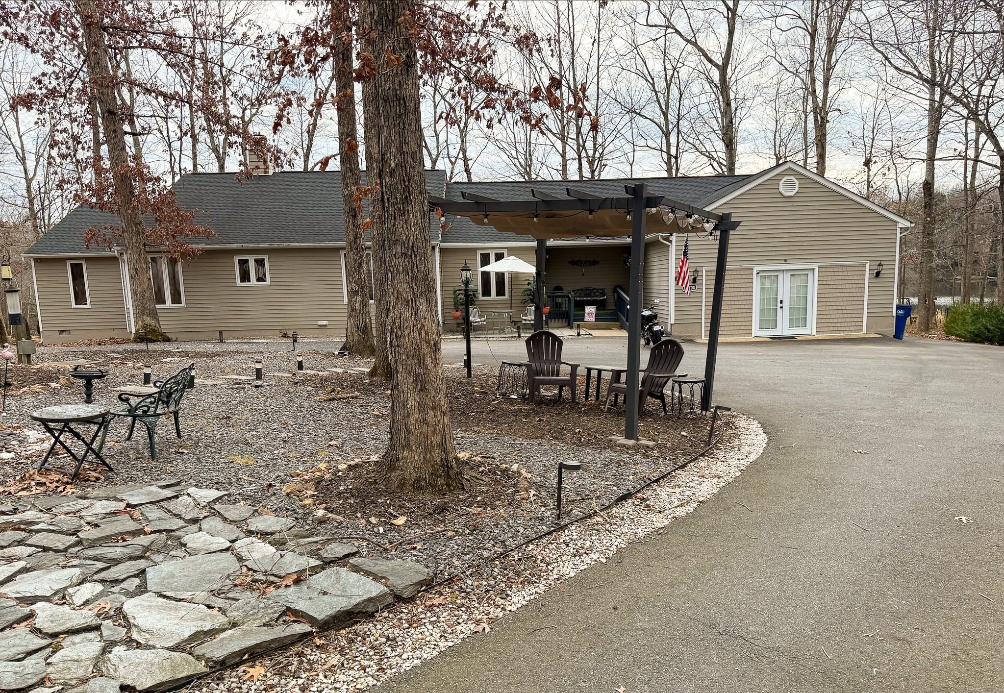 Outdoor view of a single‑story tan house with a pergola, patio seating, and surrounding trees belonging to Group Home Provider Ana Garcia in Spotsylvania, Virginia.
