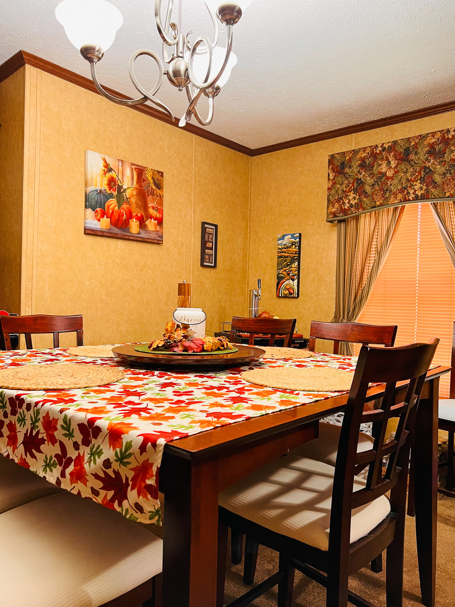 A dining room with a large wooden table set with a patterned tablecloth and surrounded by chairs inside the home of Group Home Providers Cory and Jessica Berger in Bedford County, Virginia.