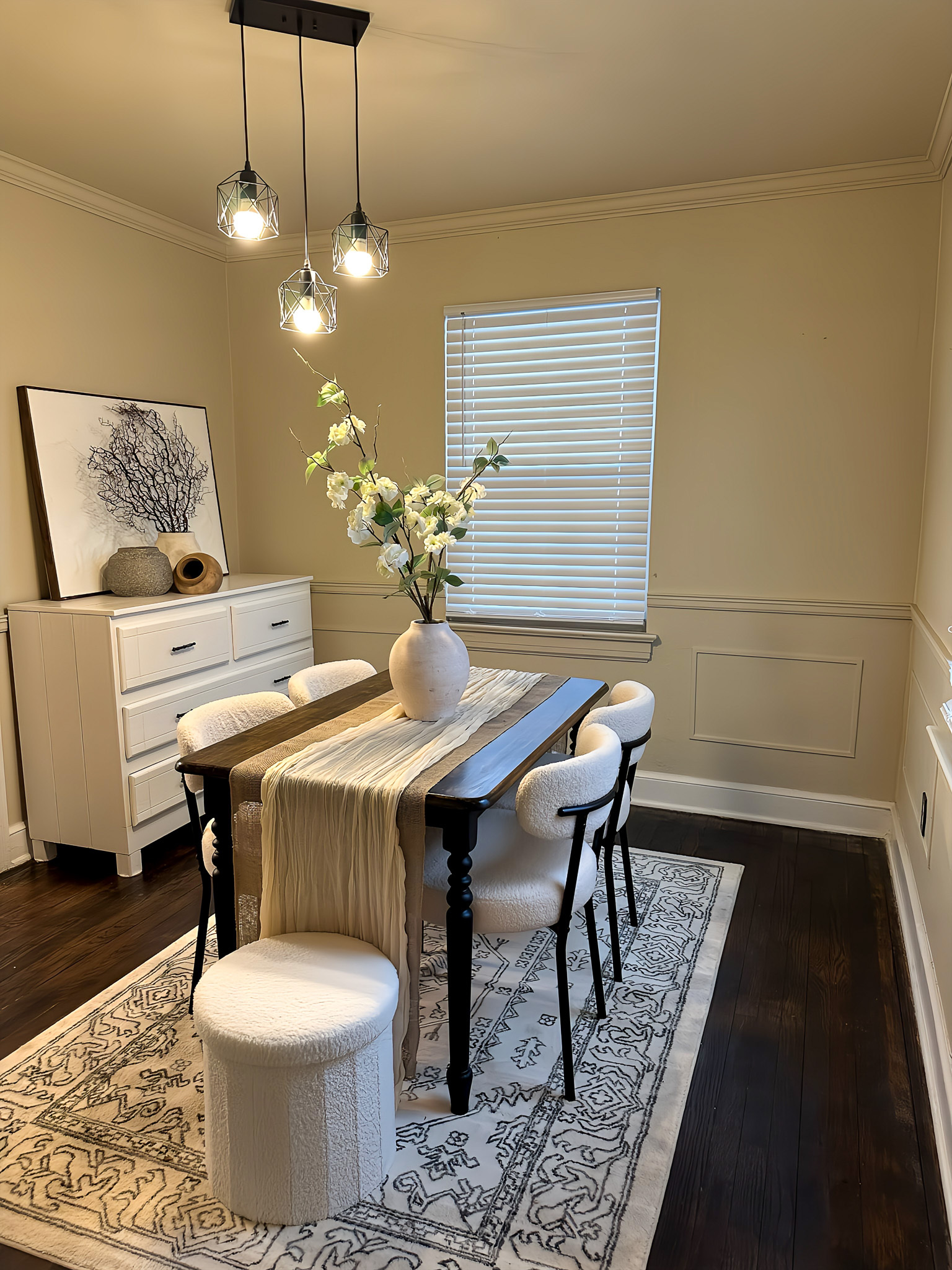 A dining room with a light wooden table, cushioned chairs, a rug underneath, and a dresser holding decor against the wall inside the home of Sponsored Residential Providers Gia & Celia Calloway in Roanoke, Virginia.