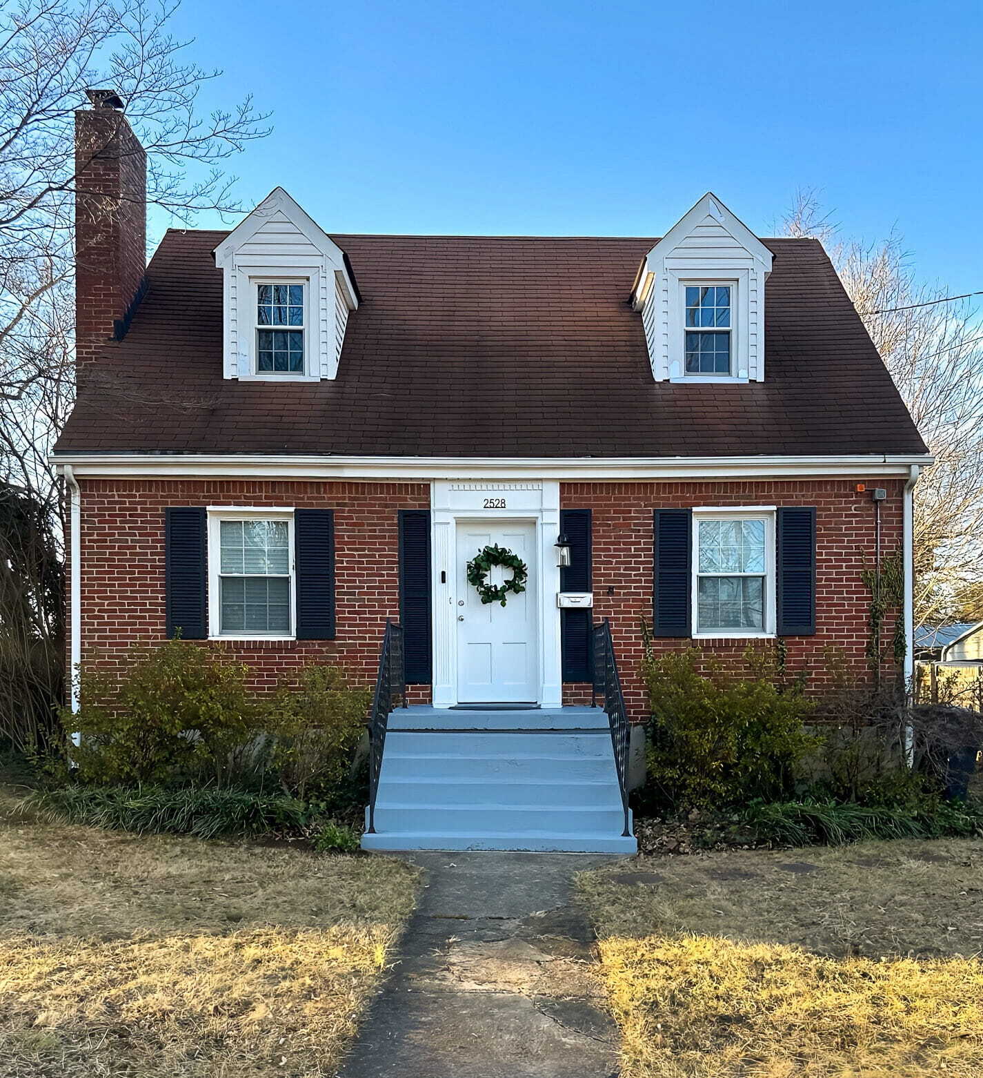 A small brick house with dormer windows, a front door with a wreath, and a short stairway leading to a narrow walkway belonging to Sponsored Residential Providers Gia & Celia Calloway in Roanoke, Virginia.