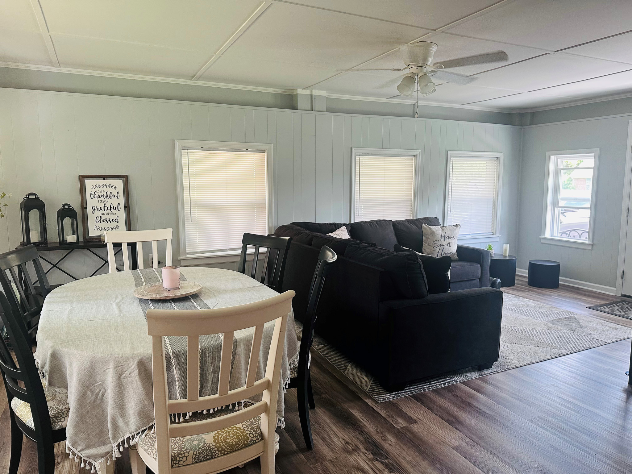 Open dining and living space with table and chairs, sectional sofa, multiple windows, and natural light throughout inside the home of Sponsored Residential Providers Casey and Fred Doswell in Lynchburg, VA.
