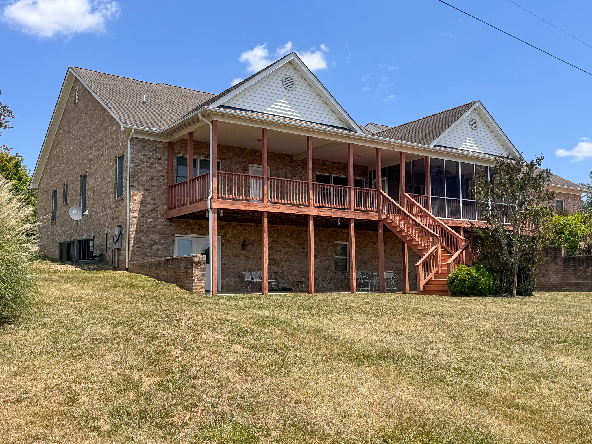 Brick home with covered back porch and wide yard on a sunny day belonging to Sponsored Residential Provider Clayton Lawson in Amherst, VA