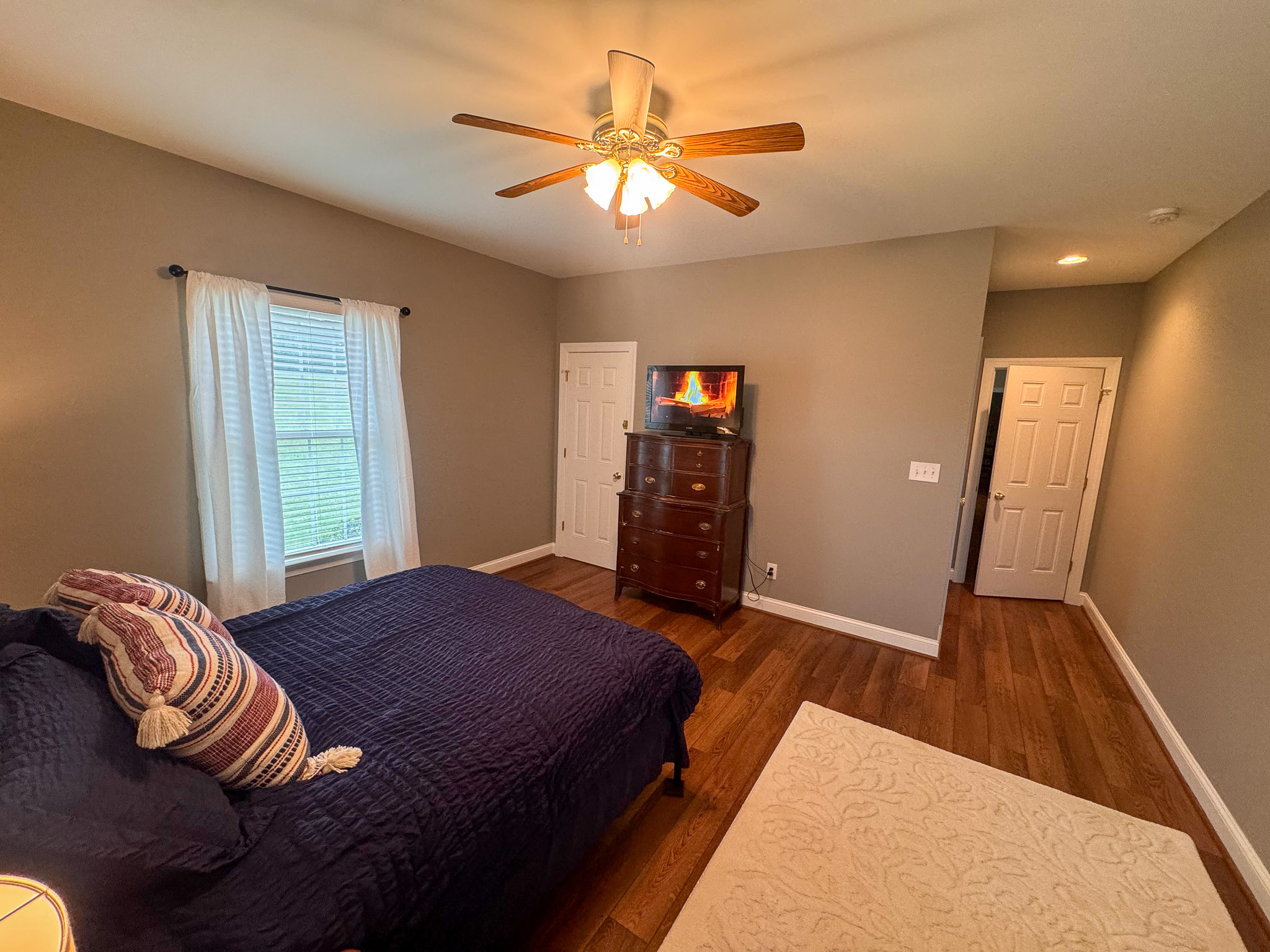 Bedroom with bed, ceiling fan, TV on dresser, and closet doors inside the home of Sponsored Residential Provider Clayton Lawson in Amherst, Virginia.