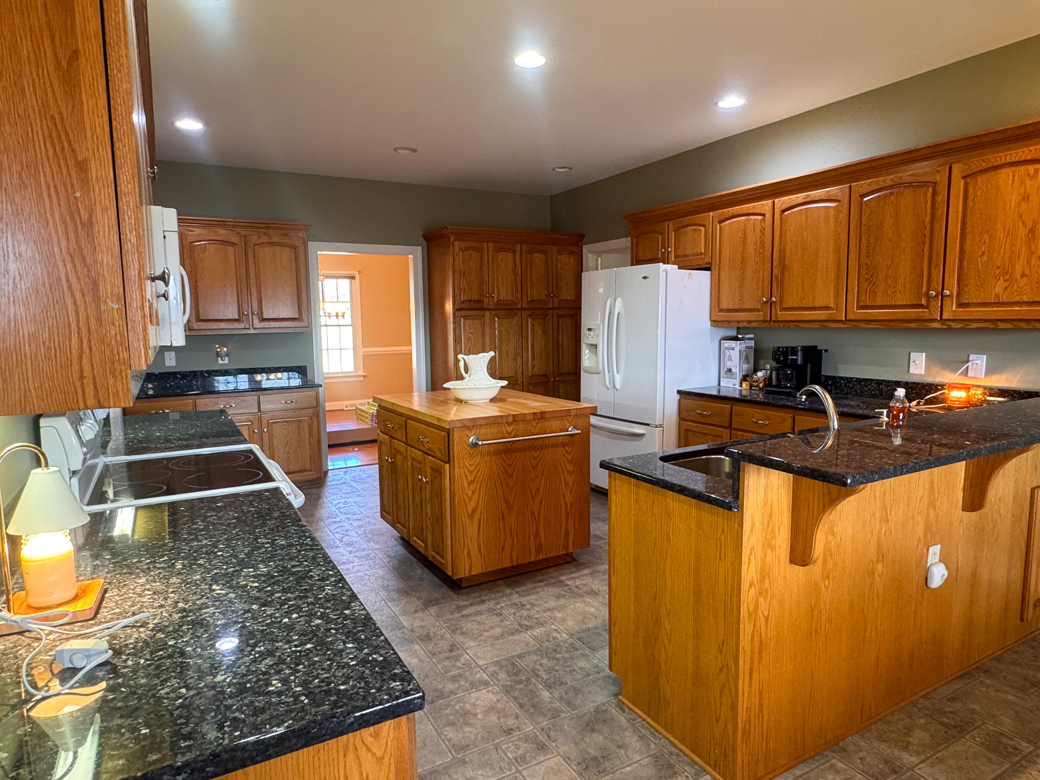 Kitchen with wood cabinets, black countertops, island, and stainless-steel appliances inside the home of Sponsored Residential Provider Clayton Lawson in Amherst, Virginia.