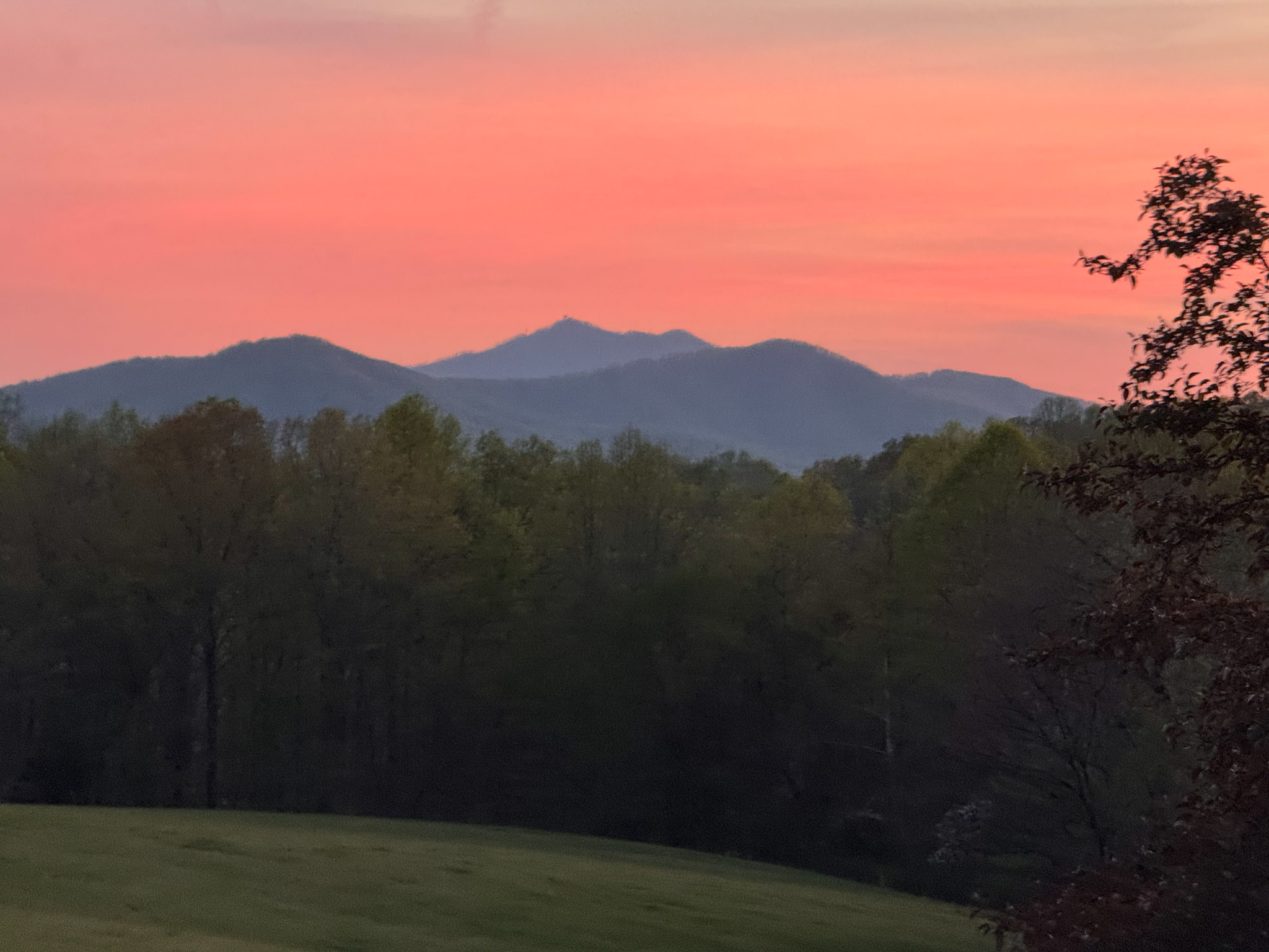 Mountain range at sunset with pink-orange sky above tree line outside the home of Sponsored provider Clayton Lawson in Amherst, VA.