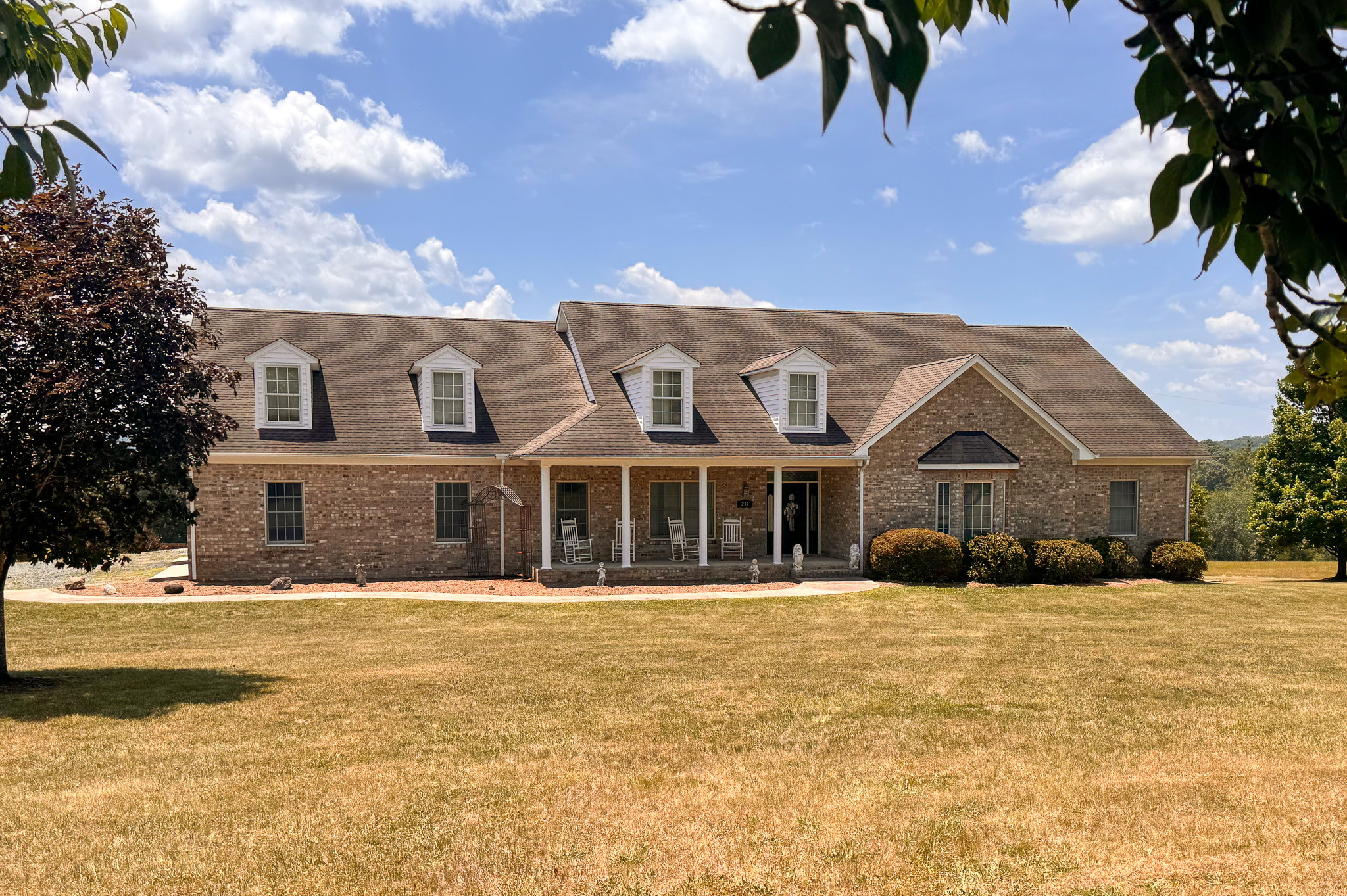 Large brick house with front porch, dormer windows, and landscaped lawn belonging to Sponsored Residential Provider Clayton Lawson in Amherst, VA