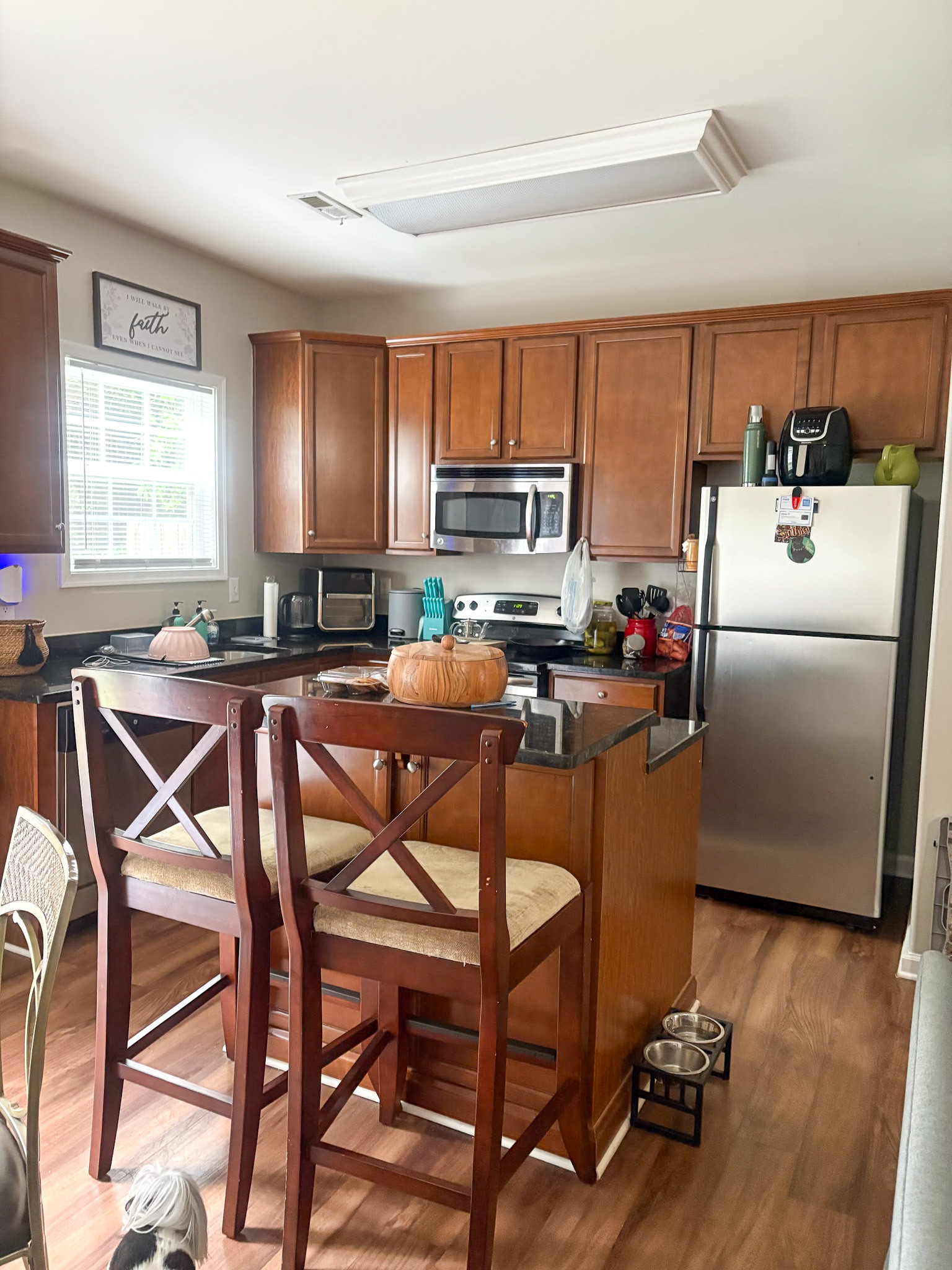 Modern kitchen with wooden cabinets, stainless steel appliances, and a small island with bar seating inside the home of Sponsored Residential provider Cynthia Kimbrough-Mabry in Chester, Virginia