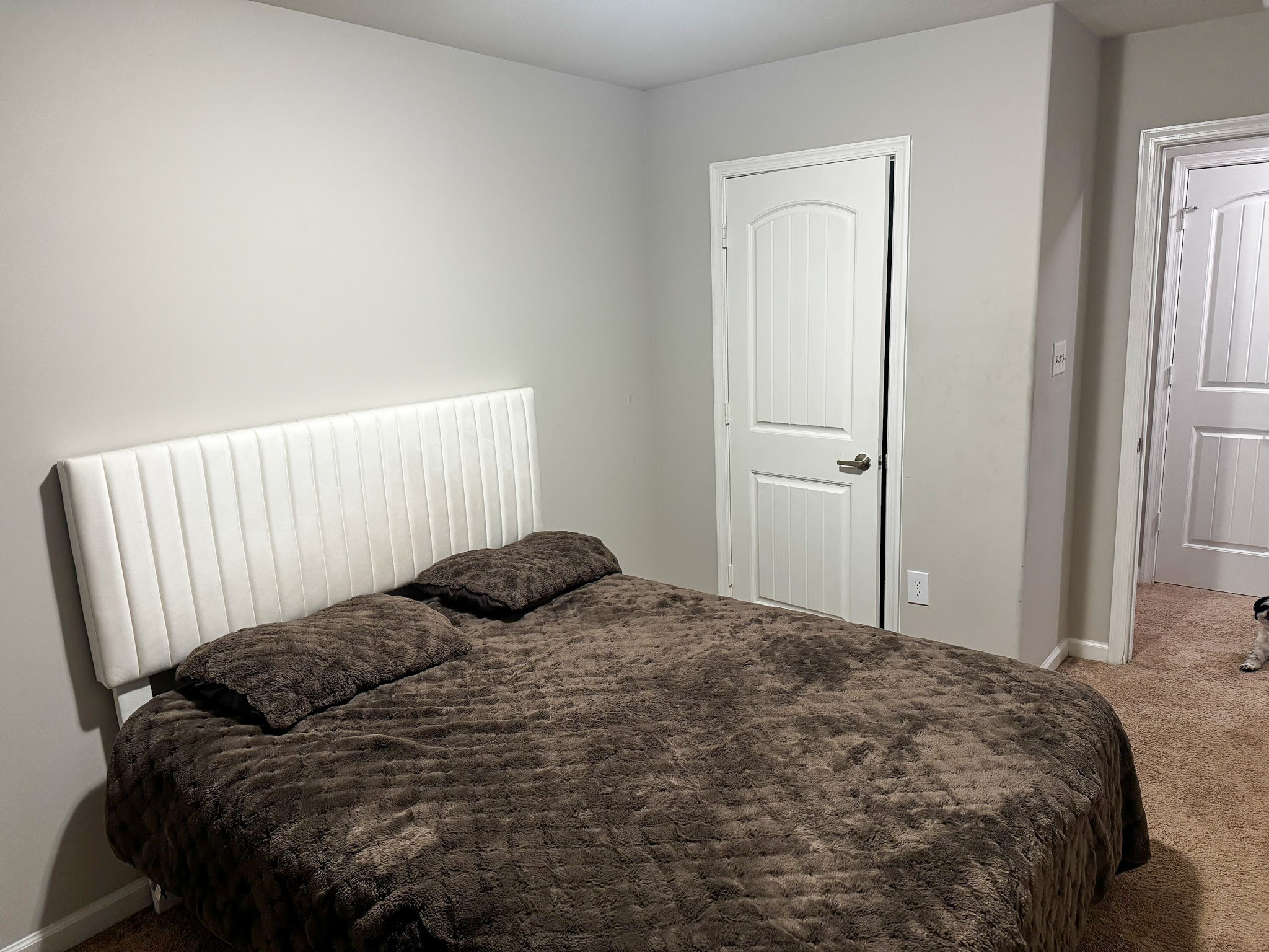 Neutral bedroom with a bed, window with blinds, and carpeted flooring inside the home of Sponsored Residential provider Cynthia Kimbrough-Mabry in Chester, Virginia