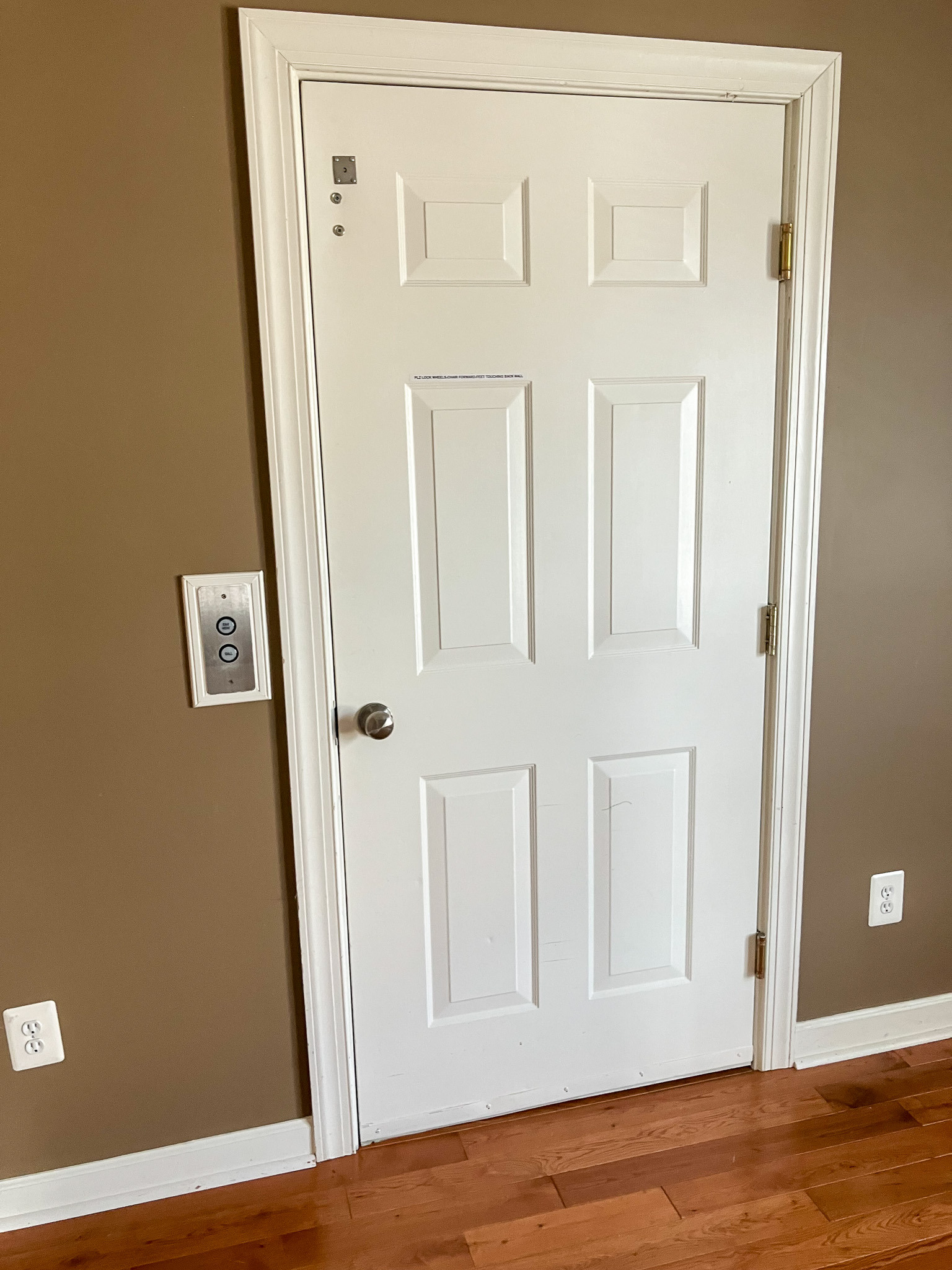 White interior door with accessible push-button controls mounted on the wall beside it belonging to the Agency operated group home names Deep Creek in Fredericksburg, Virginia.