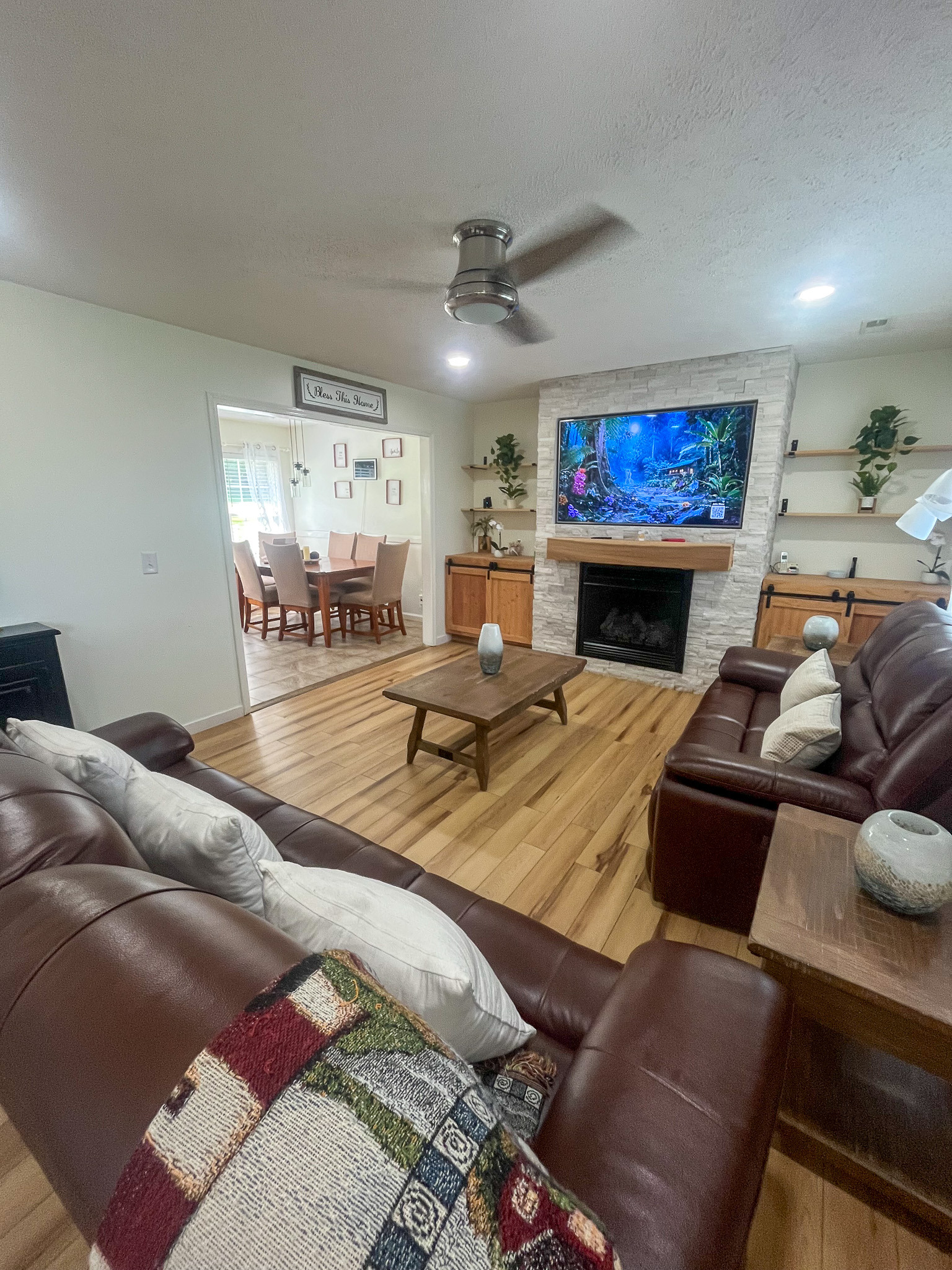 Living room with leather seating, wood flooring, a fireplace, and an adjacent dining area. This is the home of Sponsored Residential Provider Delmy Sexton in Woodlawn, VA.