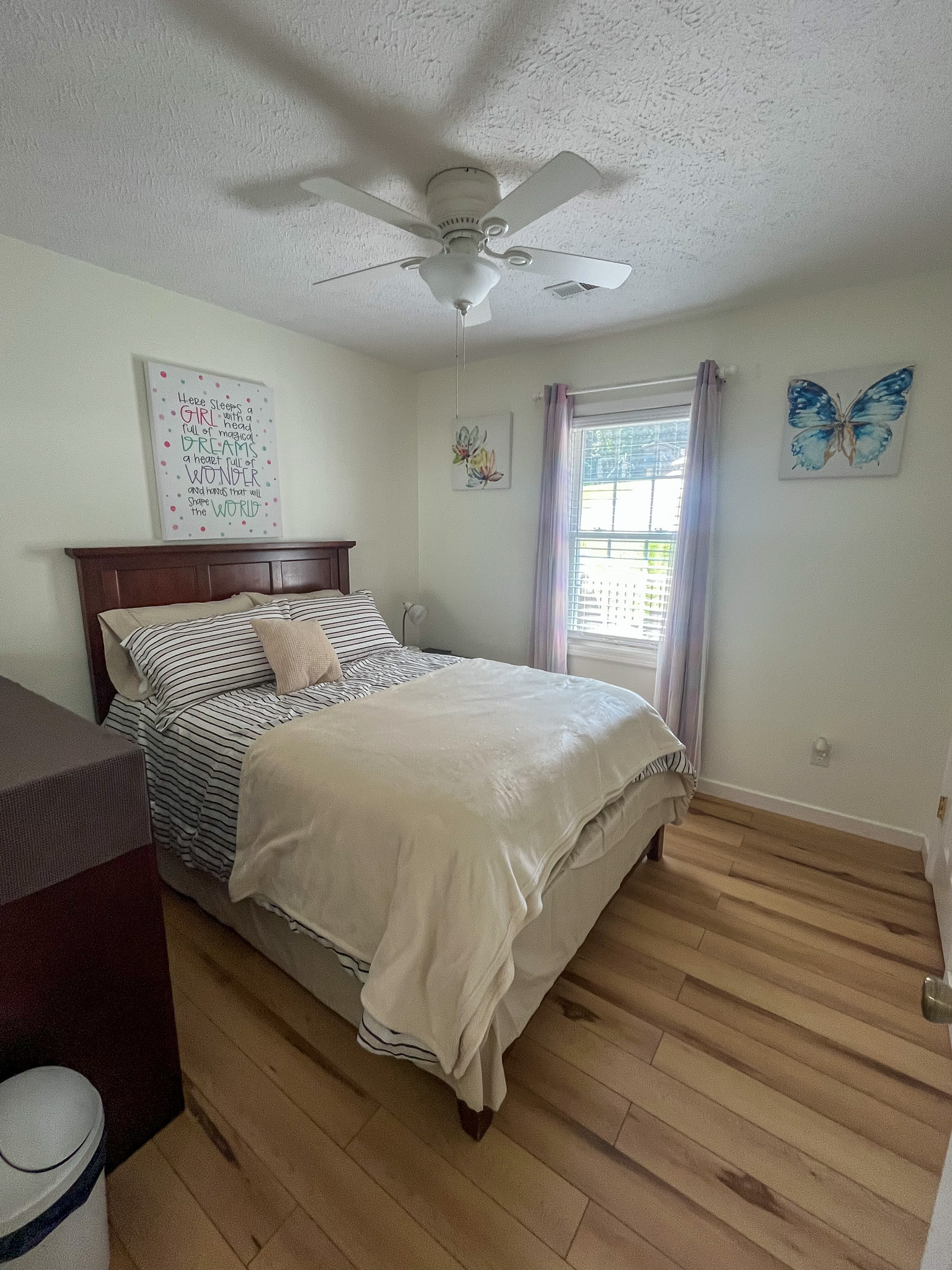Bright bedroom with a full-size bed, window, ceiling fan, and light-colored flooring. This is the home of Sponsored Residential Provider Delmy Sexton in Woodlawn, VA.