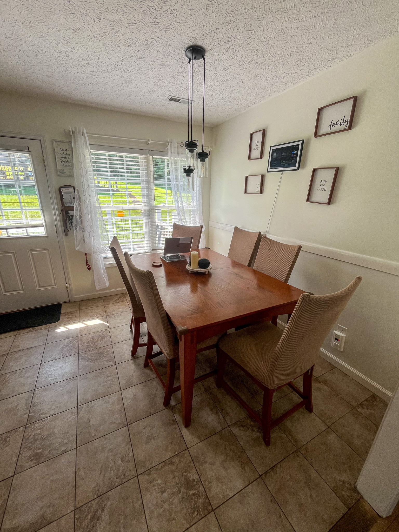 Dining area featuring a wooden table with seating for six, large windows, and natural light. This is the home of Sponsored Residential Provider Delmy Sexton in Woodlawn, VA.
