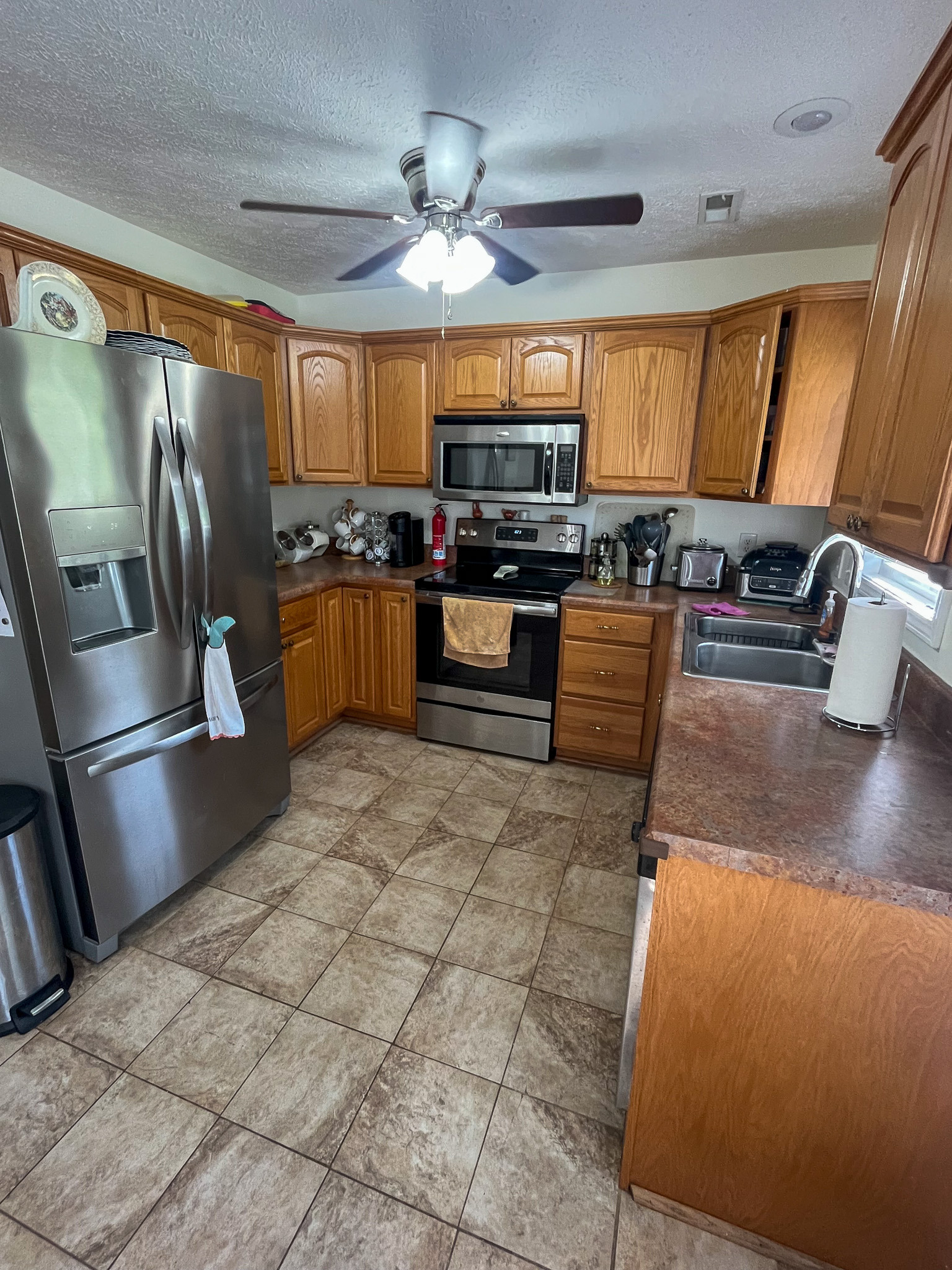 Kitchen with wood cabinetry, stainless steel appliances, ample counter space, and tile flooring. This is the home of Sponsored Residential Provider Delmy Sexton in Woodlawn, VA.