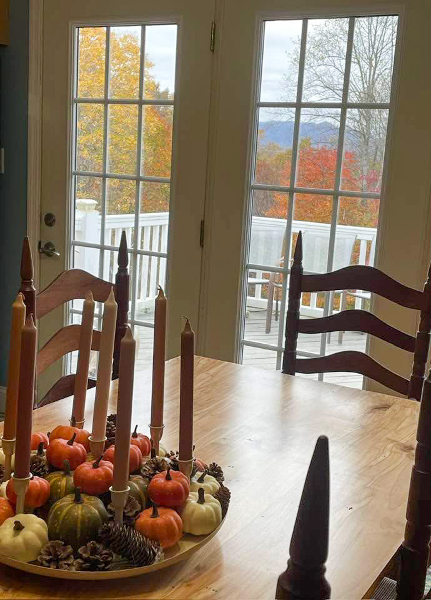 A dining table decorated with pumpkins and candles beside glass doors overlooking a deck and colorful trees in the home of Group Home Providers Kim and Rick Duncan in Patrick Springs, Virginia.
