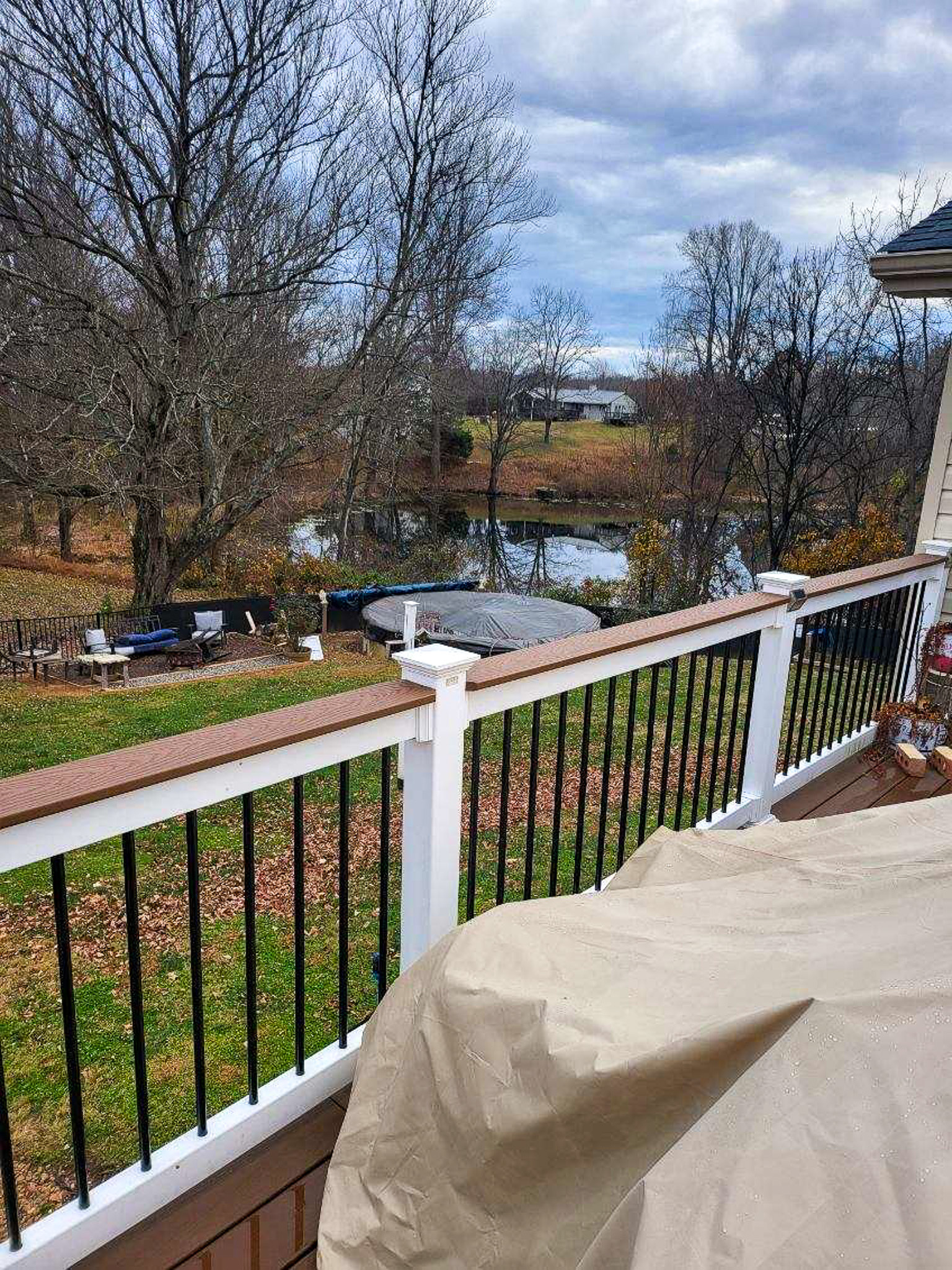 A deck railing overlooks a yard with bare trees and a small pond in the distance at the home of Sponsored Residential Providers Scott and Tedra Flanders in Lynchburg, Virginia.