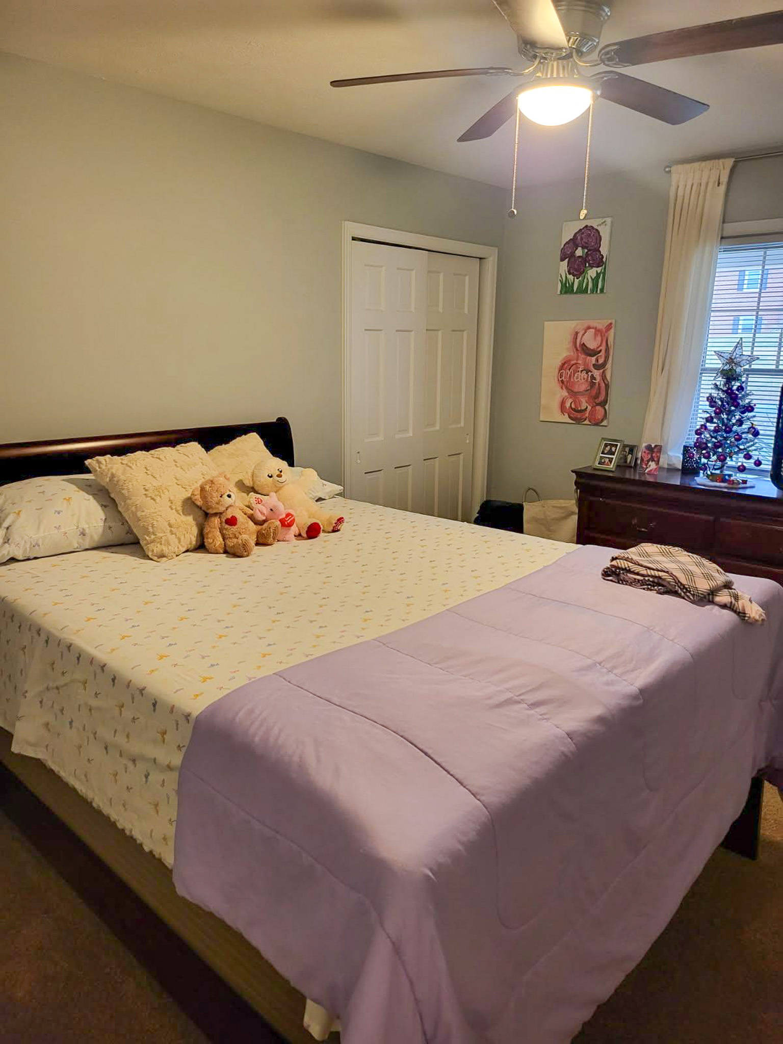 A neatly made bed with pastel bedding sits beside a dresser and a small decorated tree near the window inside the home of Sponsored Residential Providers Scott and Tedra Flanders in Lynchburg, Virginia.
