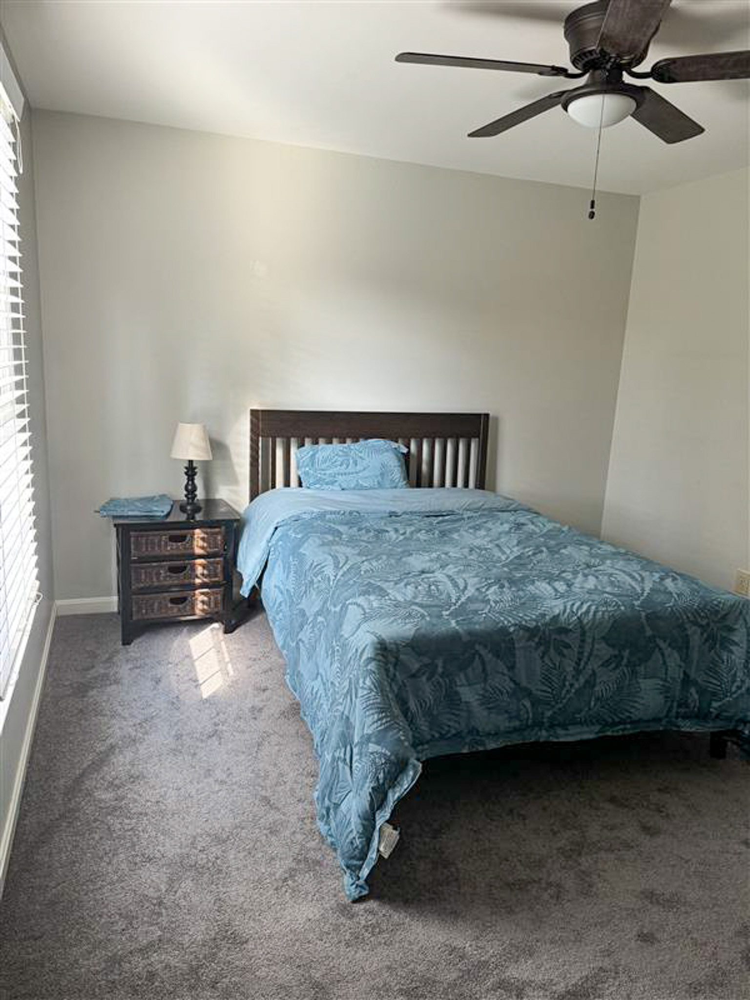 Bedroom with full-size bed, blue bedding, ceiling fan, and nightstand inside the home of Sponsored Residential Provider Gamu Gomo in Woodbridge, Virginia.