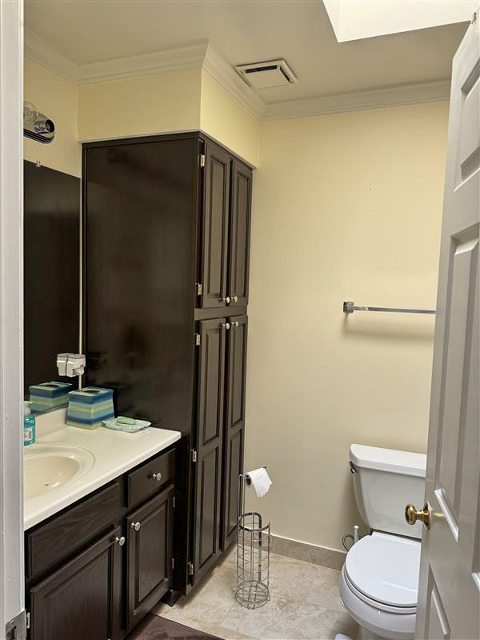 Bathroom with toilet, sink, tall storage cabinet, and neutral wall inside the home of Sponsored Residential Provider Gamu Gomo in Woodbridge, Virginia.