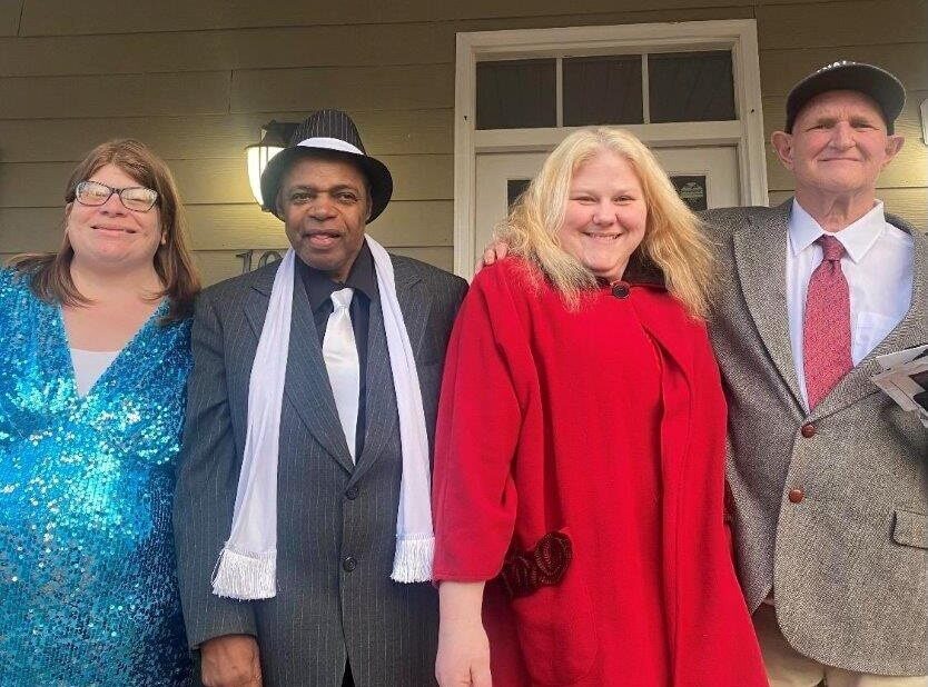 two men and two women in nice outfits standing on front porch of group home