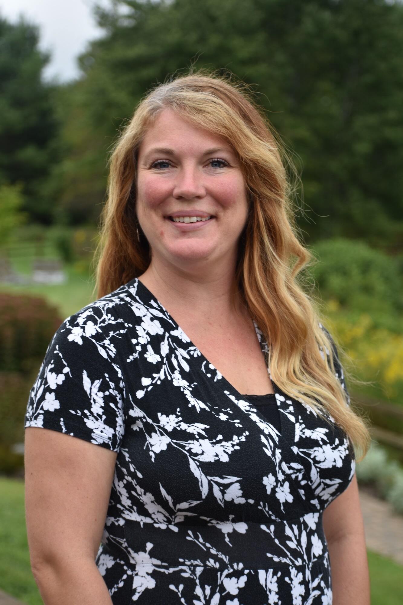 Admissions Coordinator Heather Sowers smiling in front of greenery