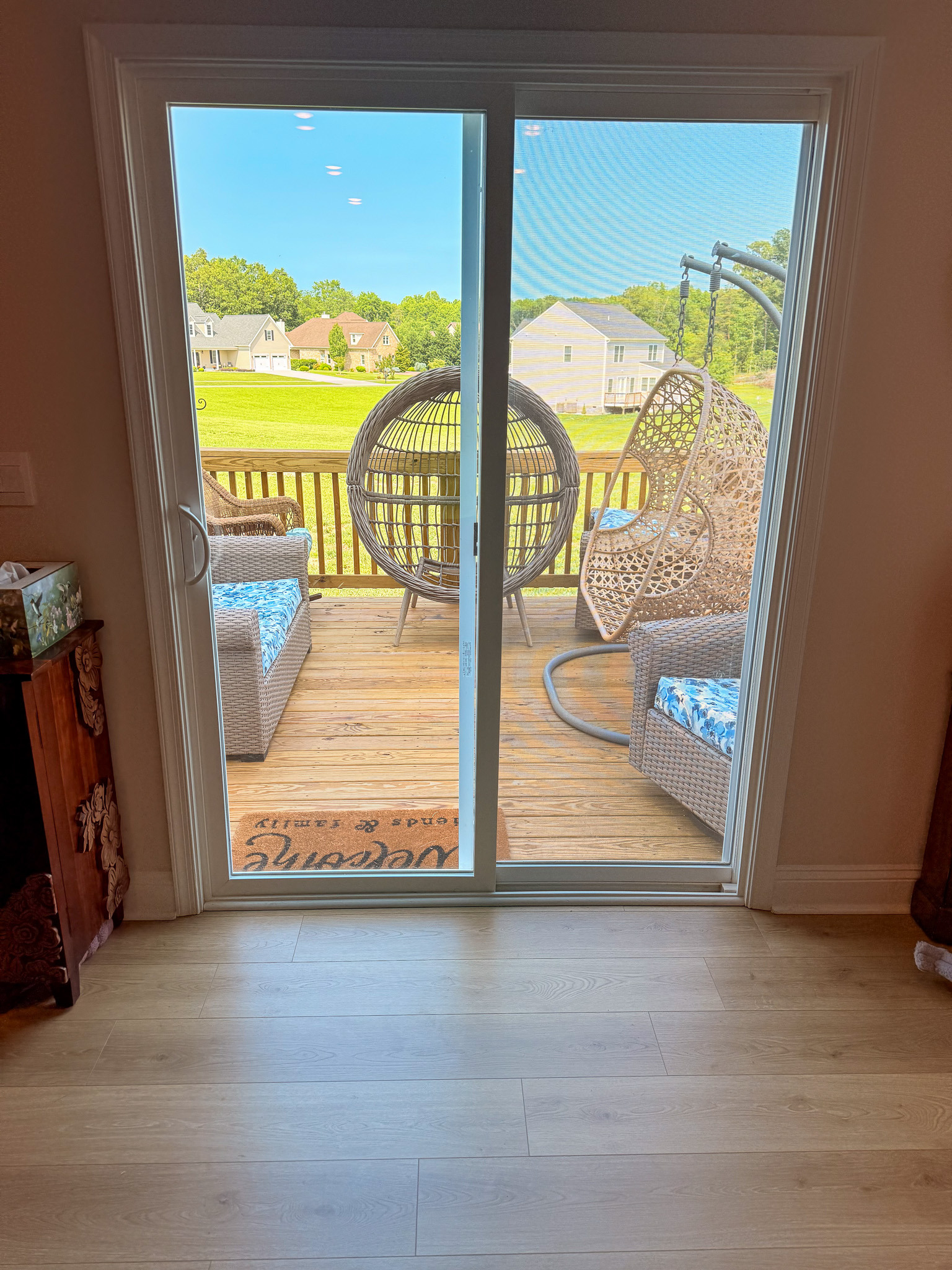Sliding glass door opening to a wooden deck with outdoor seating and a hanging chair overlooking a grassy yard inside the home of Group Home provider Traci Burch in Staurts Draft, VA.