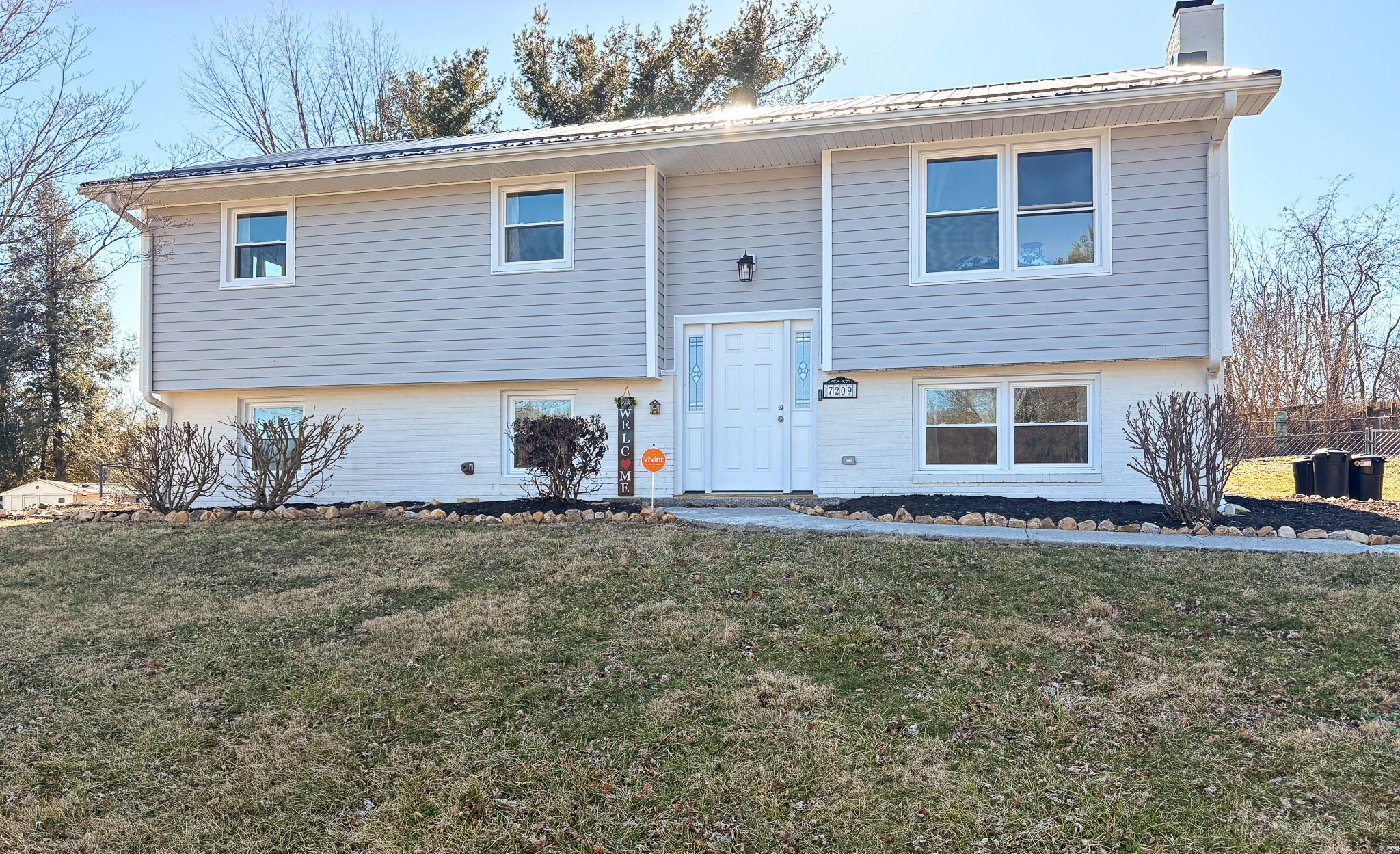 Split‑level gray home with white trim, central front entrance, and a grassy yard in a residential neighborhood belonging to Sponsored Residential Provider Destiny Branscome in New River Valley.
