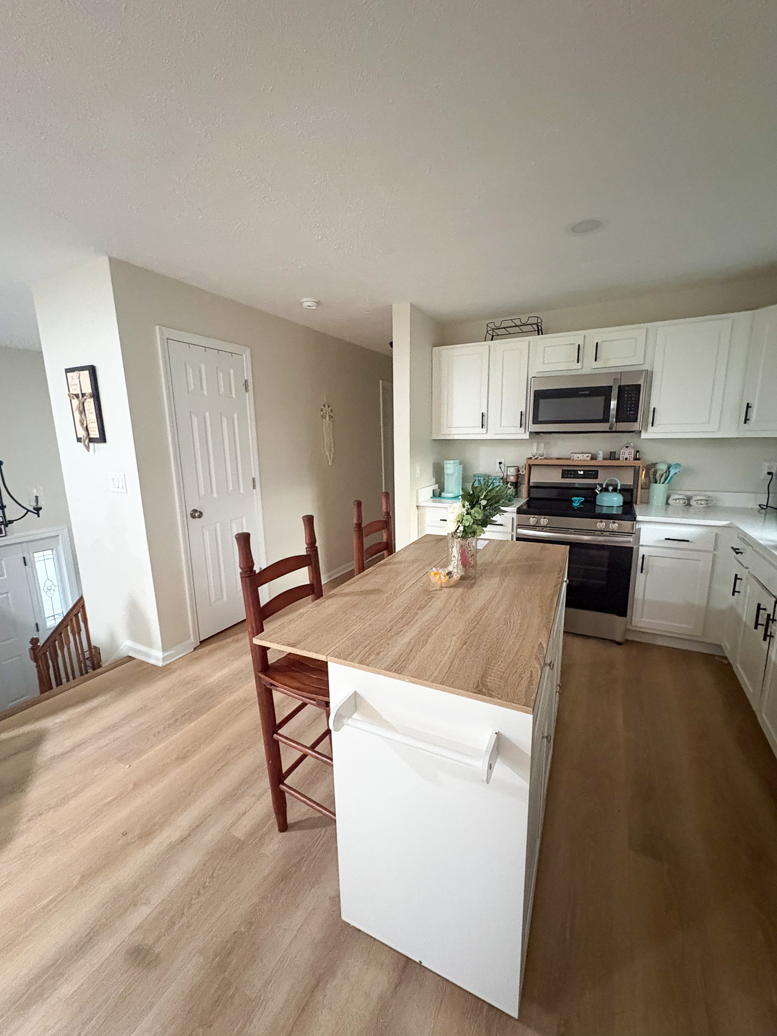 Bright, open kitchen with a central island, white cabinets, stainless steel appliances, and light wood flooring inside the home of sponsored Residential Provider Destiny Branscome in New River Valley, VA.