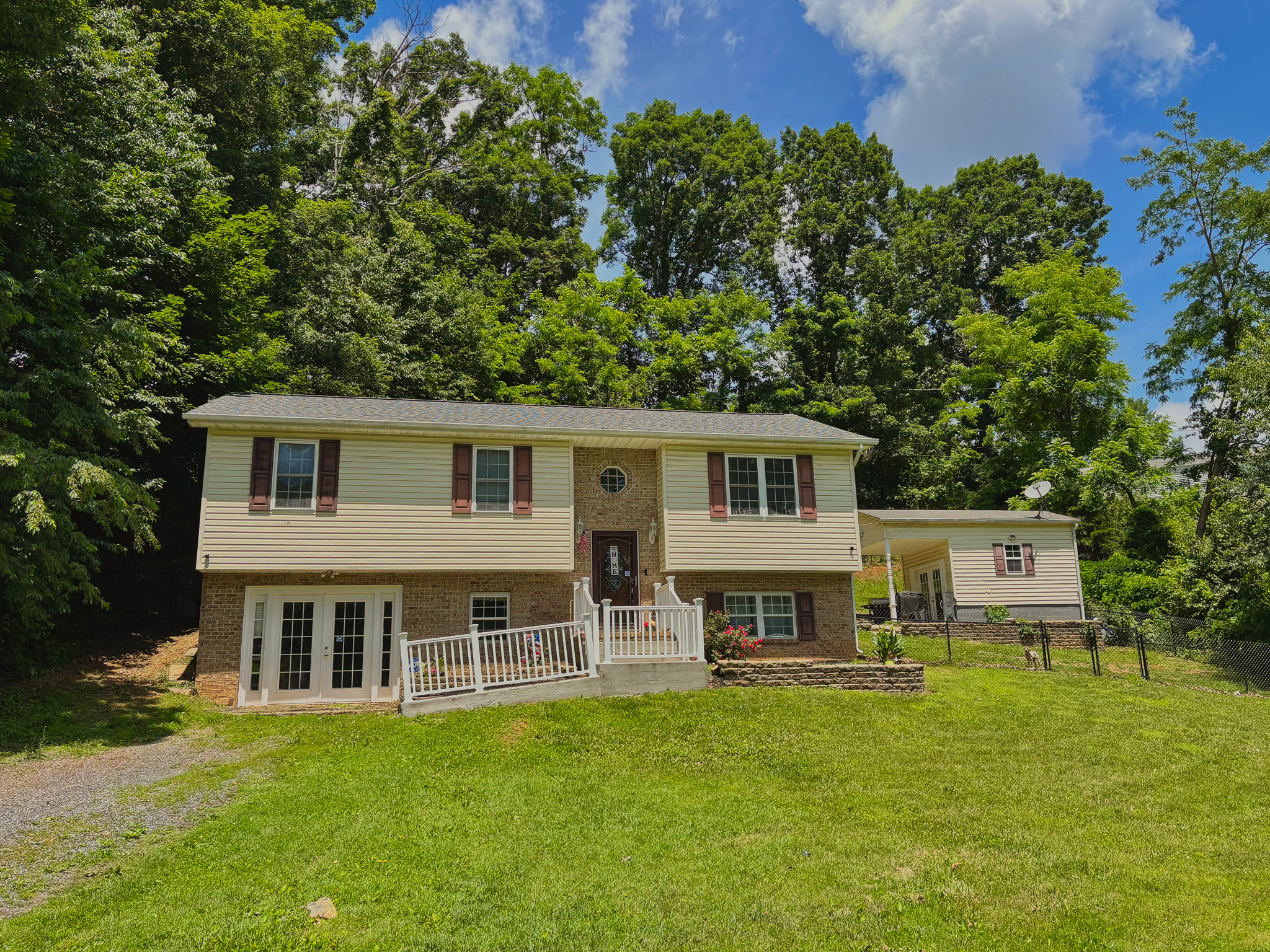 Split‑level home with brick and siding exterior, front porch, and fenced yard surrounded by trees belonging to Sponsored Residential Provider Lana Cyzicks in Staunton, Virginia.