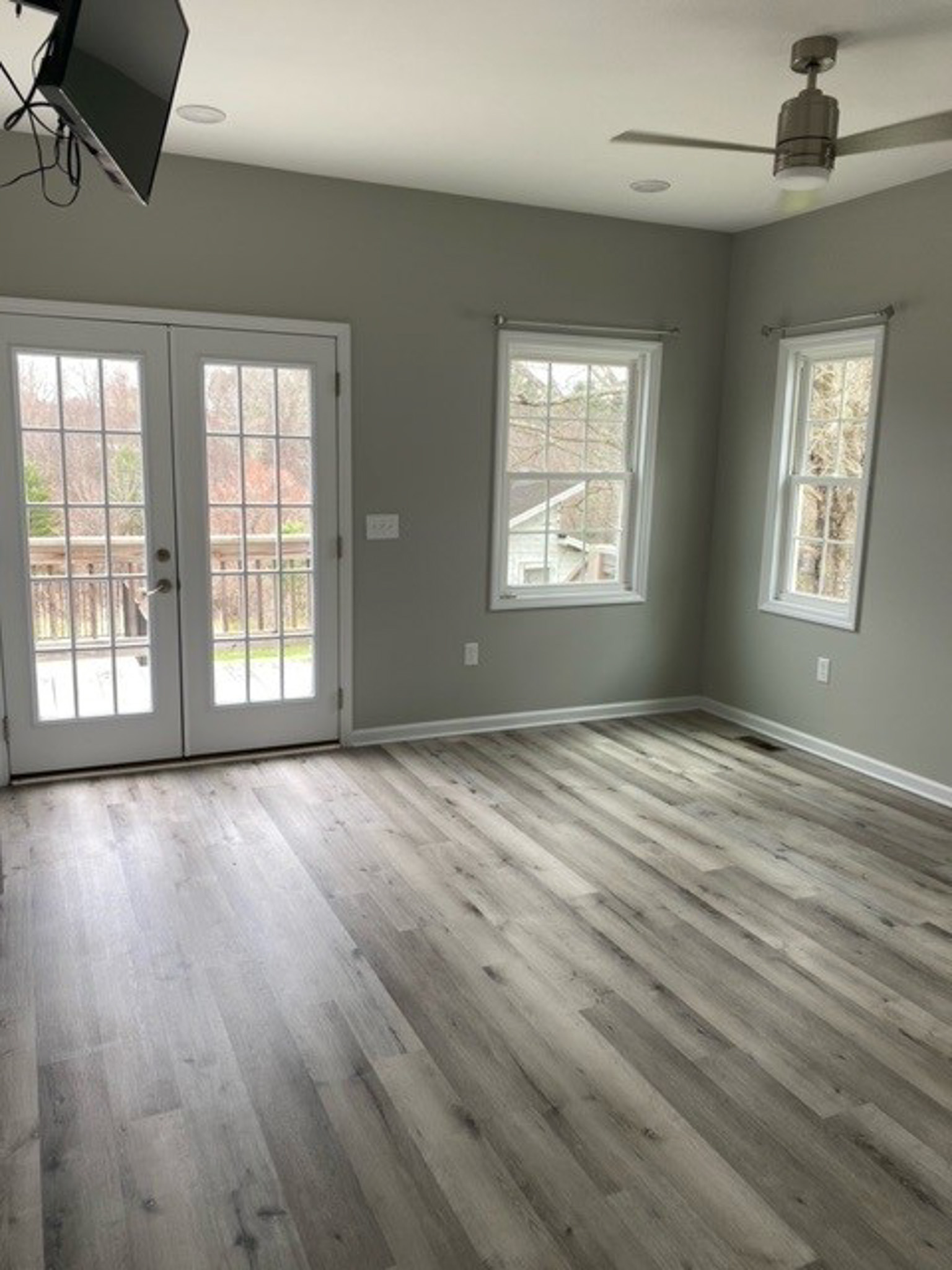 Bright bedroom at Jake and Angie Beamer’s provider group home in Hillsville, Virginia, featuring large windows, French doors, a ceiling fan, and wood-look flooring.