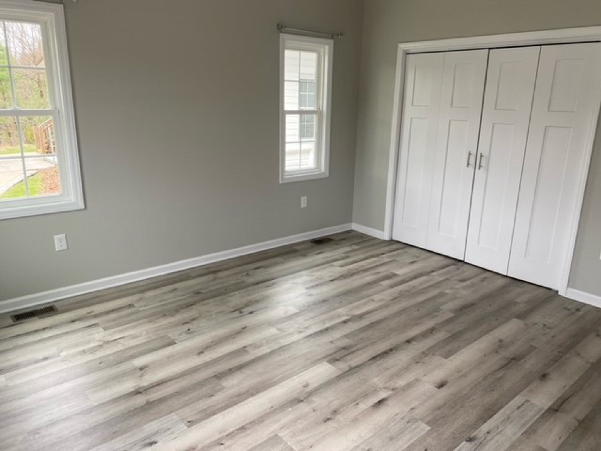Spacious bedroom at Jake and Angie Beamer’s provider group home in Hillsville, Virginia, featuring large windows, a double-door closet, and wood-look flooring.