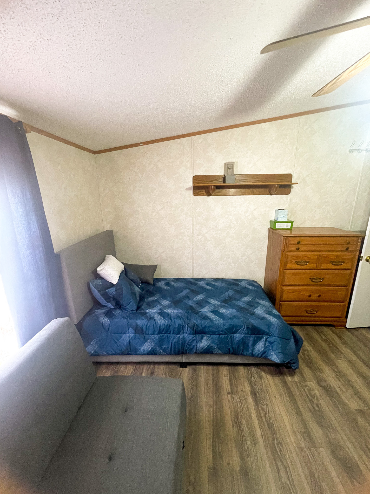 Bedroom in the home of Sponsored Residential Providers Janice and Kenny Cox in Willis, Virginia, featuring a bed, dresser, seating area, and ample open floor space.