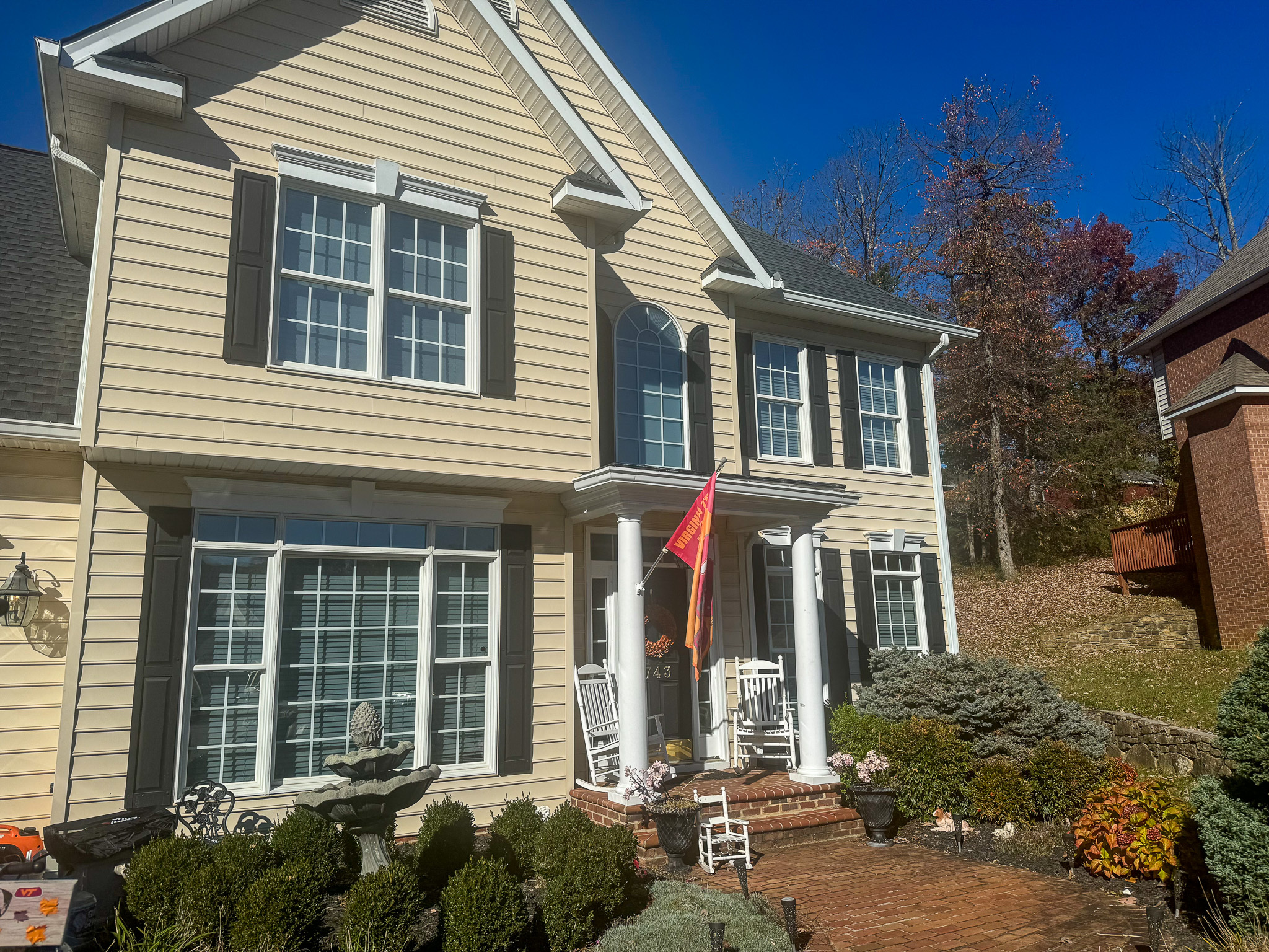 A two‑story light‑colored house with large front windows, a porch with rocking chairs, and neatly arranged shrubs and fall decorations belonging to Sponsored Residential Provider Sharon Jennings in Salem, Virginia.