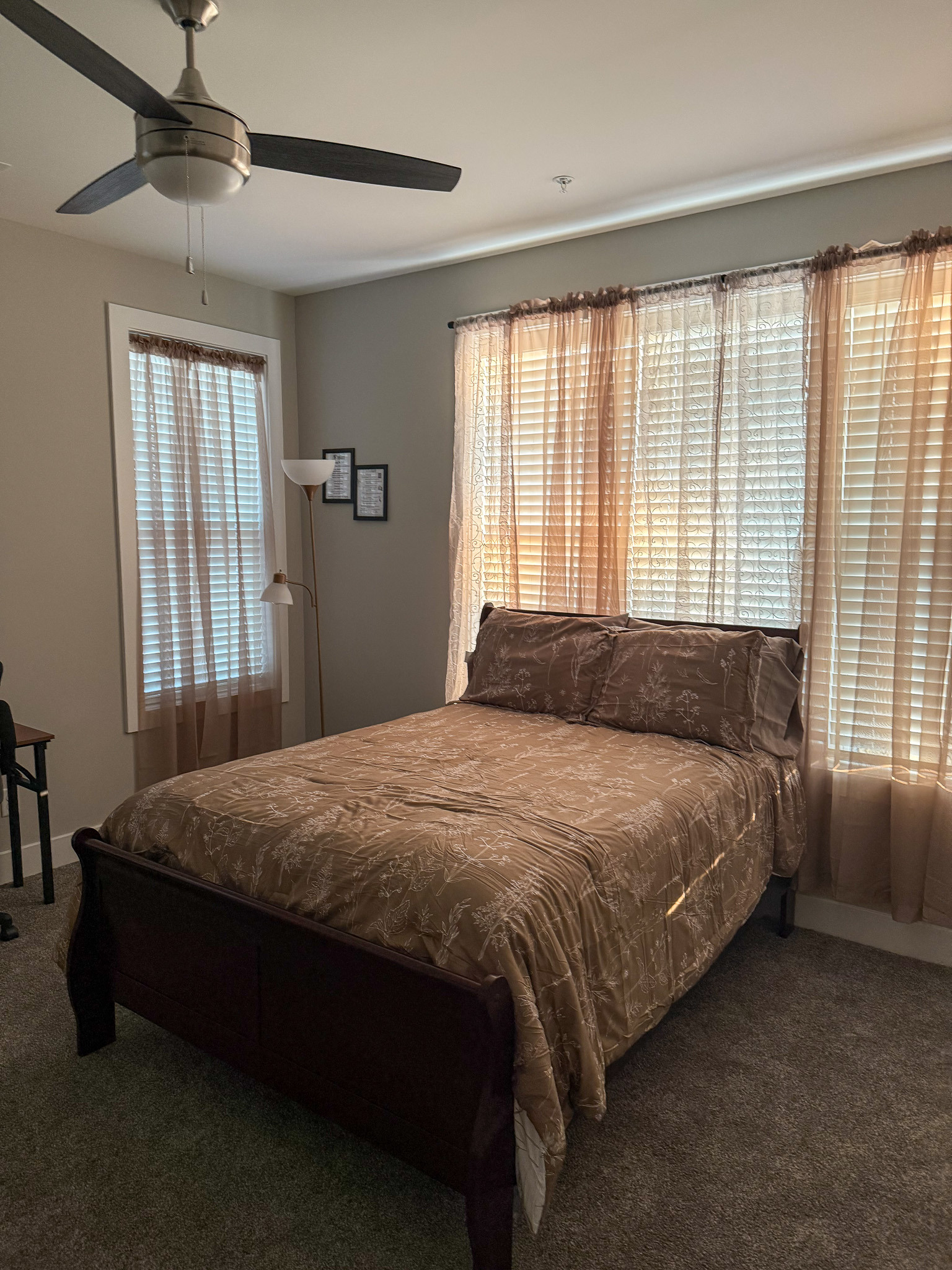 Spacious bedroom with large windows, natural light, and a ceiling fan in the home of Sponsored Residential Provider Justina Megginson in Roanoke, Virginia.