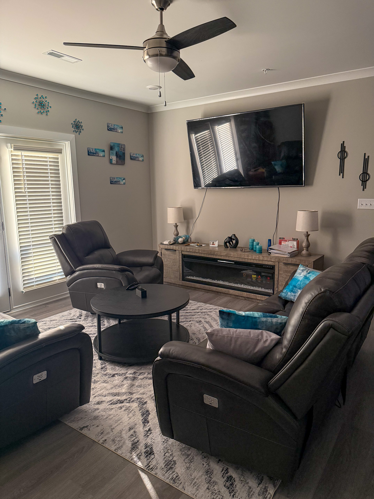 Comfortable living room with reclining seating, an entertainment center, and patio access in the home of Sponsored Residential Provider Justina Megginson in Roanoke, Virginia.