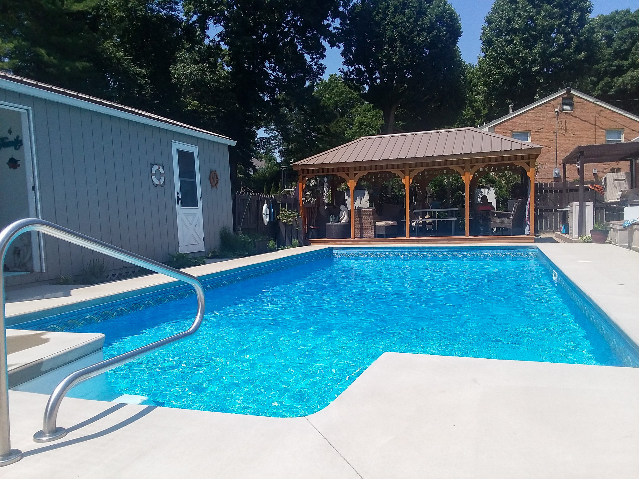 Outdoor saltwater swimming pool with metal handrail, concrete deck, and shaded gazebo seating area belonging to Sponsored Residential Provider Rhonda Kestner in Staunton, VA.