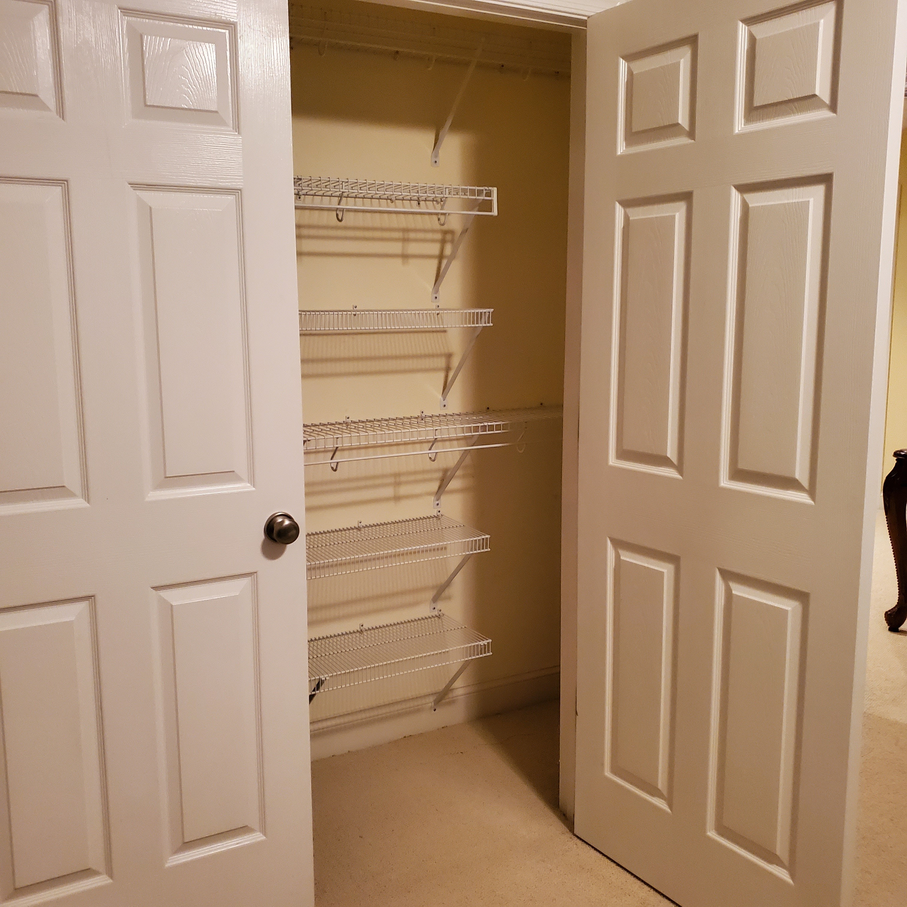 Bedroom closet with double doors open, showing empty wire shelving along the back and side walls inside the home of Group Home Providers Dayshawnna and Michael Lee in Chester, Virginia.