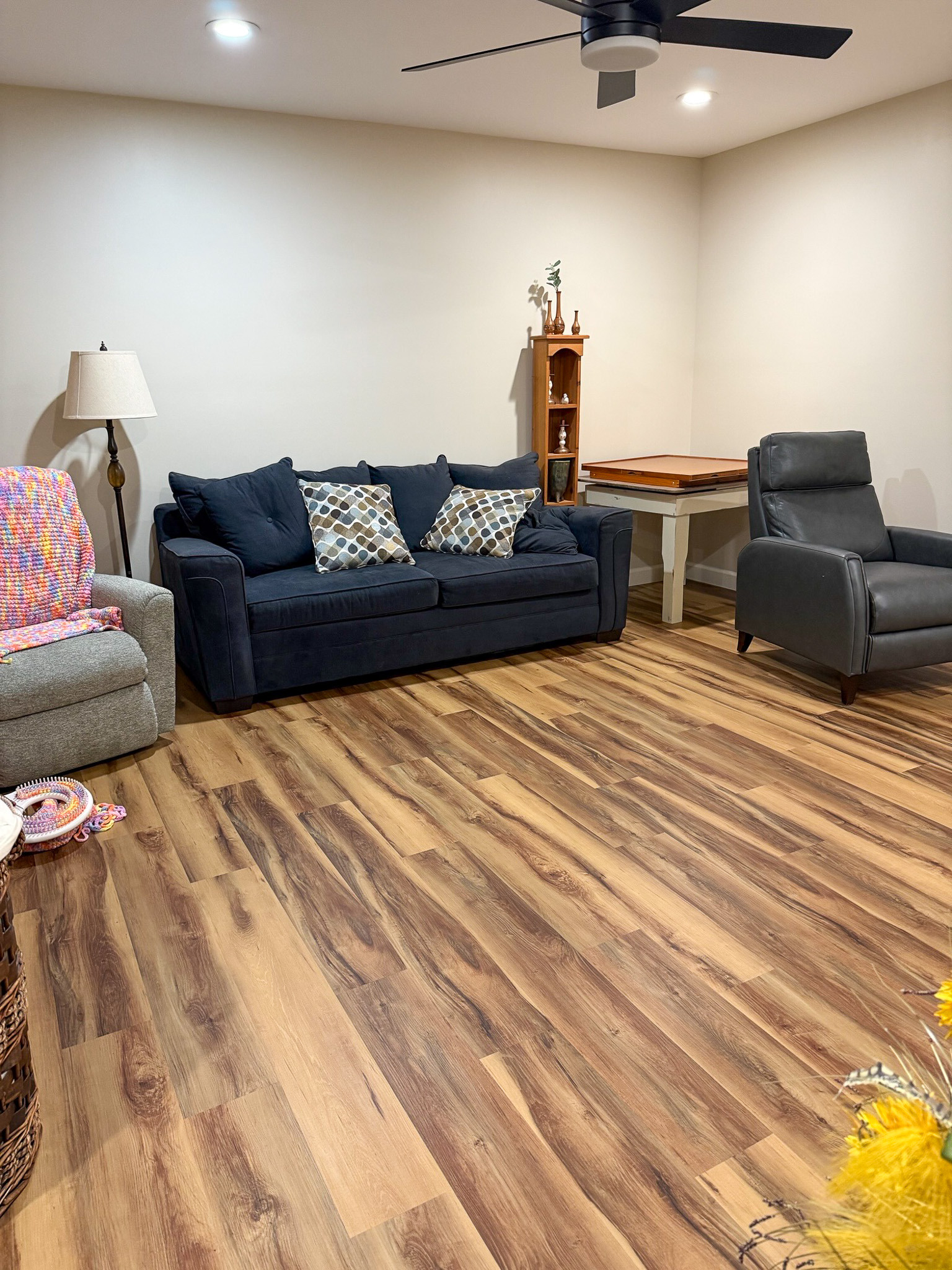 Cozy living room with wood flooring, a navy sofa, armchairs, and warm furnishings in the home of Wall Group Home provider Lisa Lohr in Harrisonburg, VA.