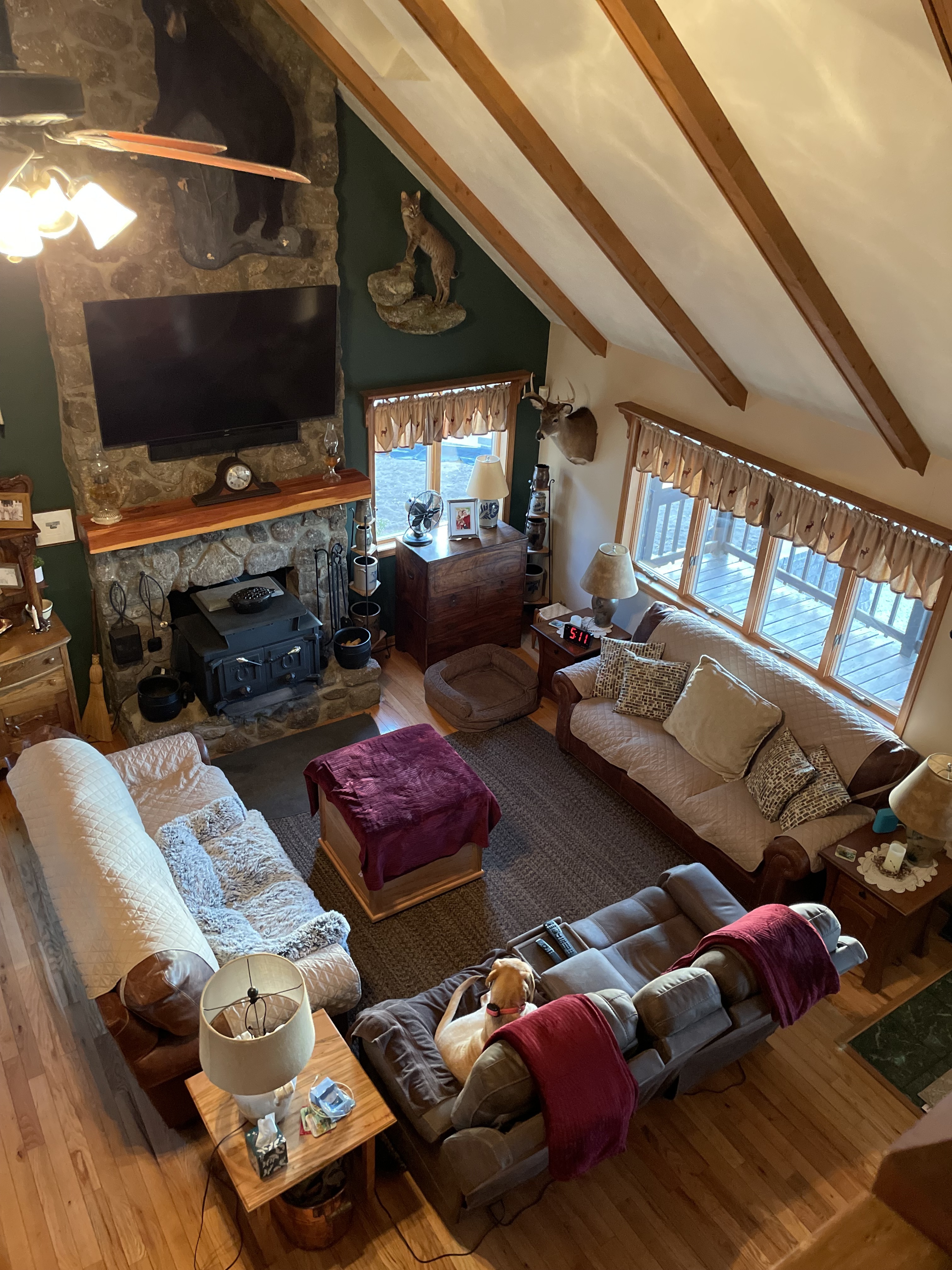 Vaulted ceiling with wooden beams overlooking living room with couches, stone fireplace, and TV as seen from landing above  inside the home of Sponsored Residential Providers Jimmy and Nancy Ayers in Monroe, Virginia.