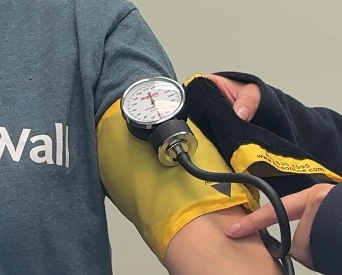 A nurse using a blood pressure cuff on a patient’s arm.