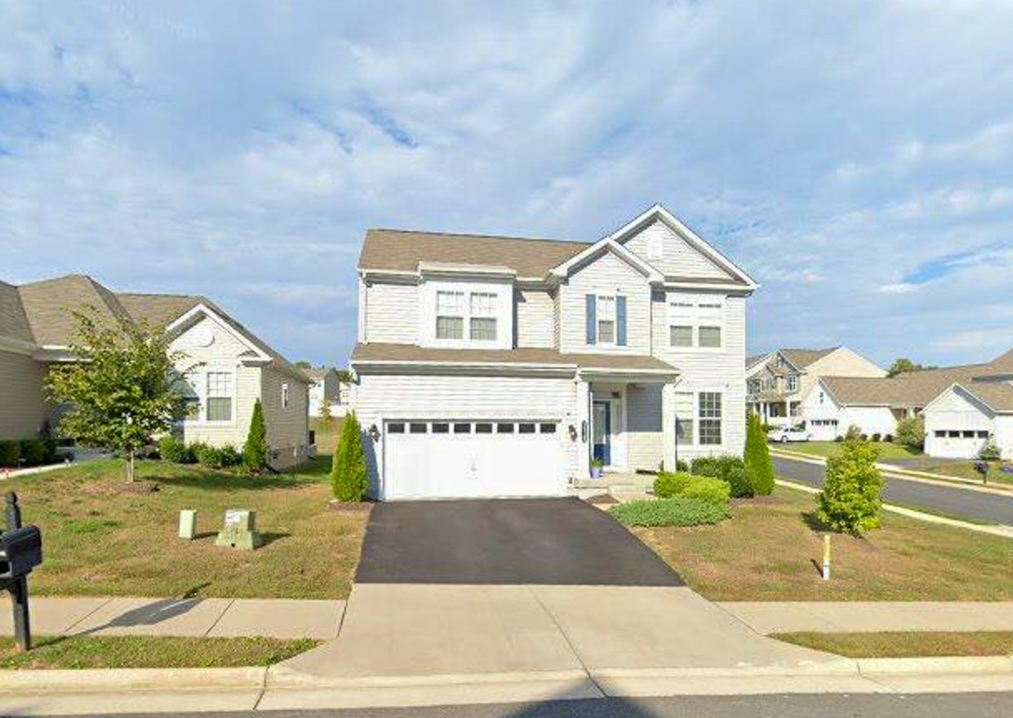 A two‑story suburban house with a two‑car garage, light‑colored siding, and a paved driveway, located on a corner lot in a residential neighborhood belonging to Torwon and Deljuan Mitchell in Fredericksburg, Virginia.